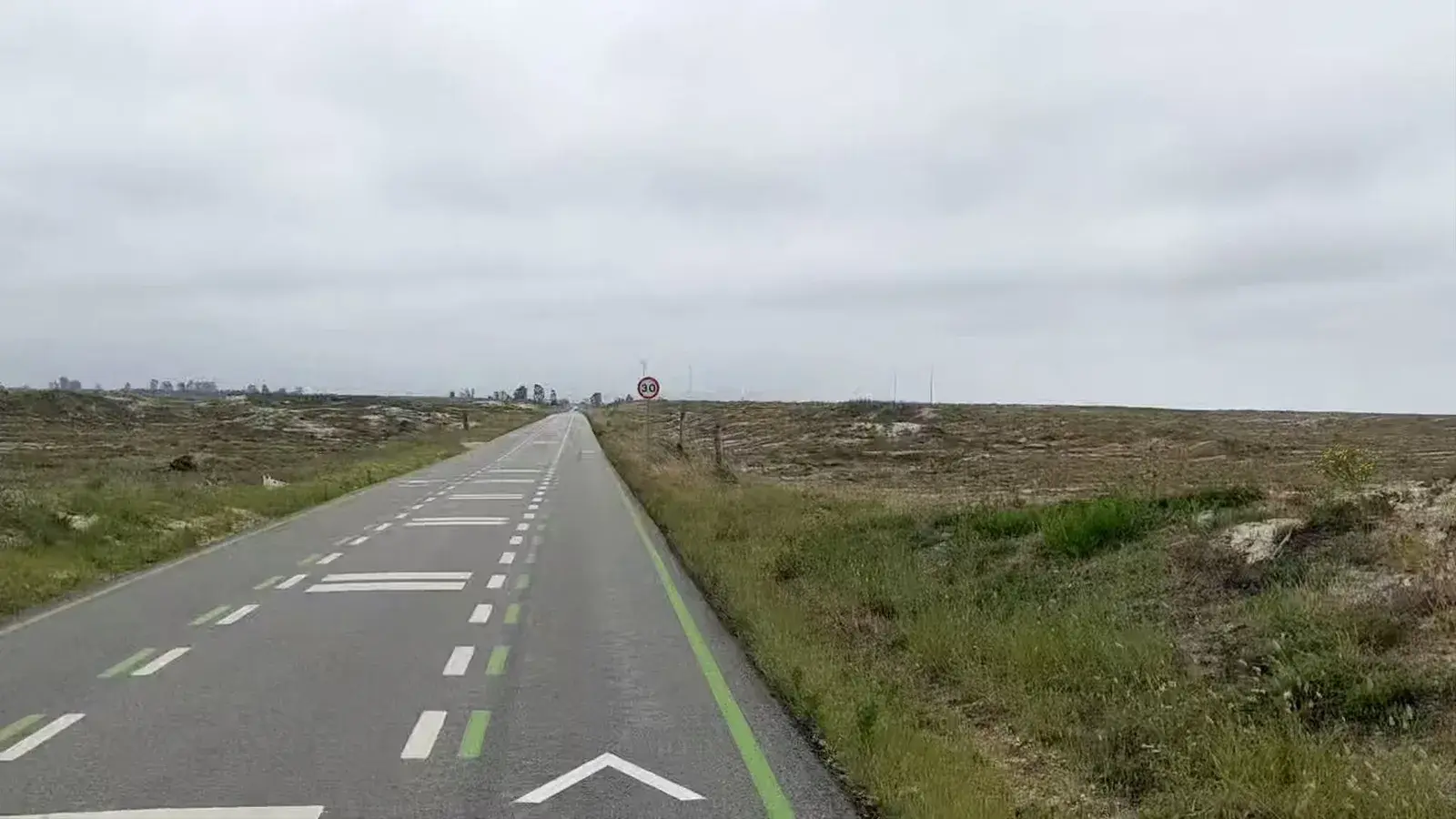 A straight green cycle lane crossing open scrubland