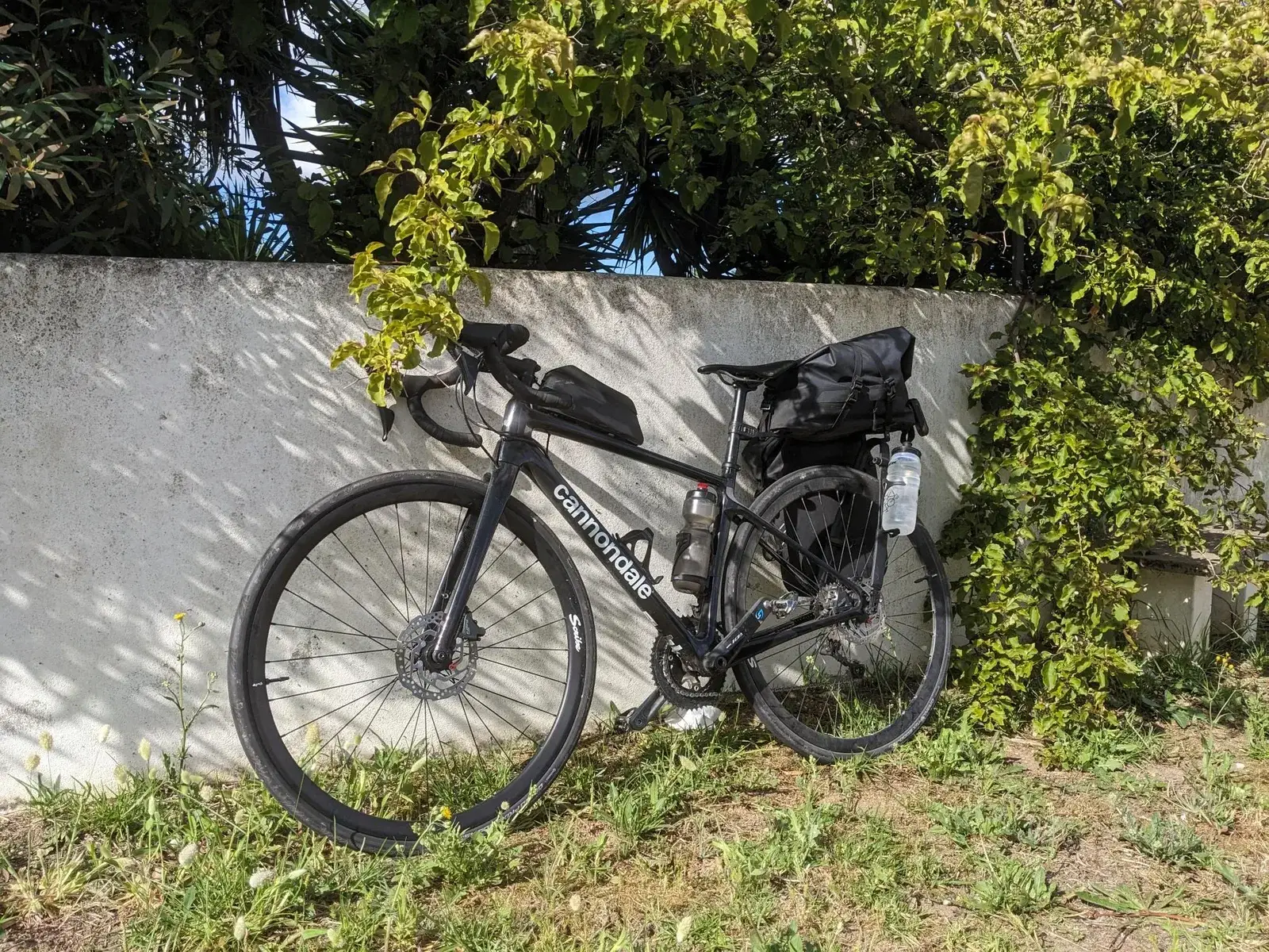 A loaded touring bicycle leaning against a white wall