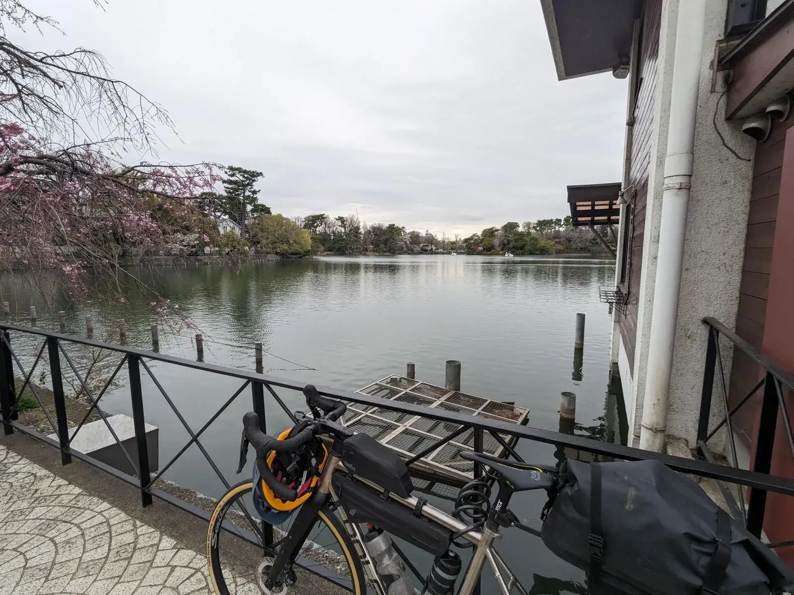 A loaded bicycle overlooking a calm river in a Japanese town