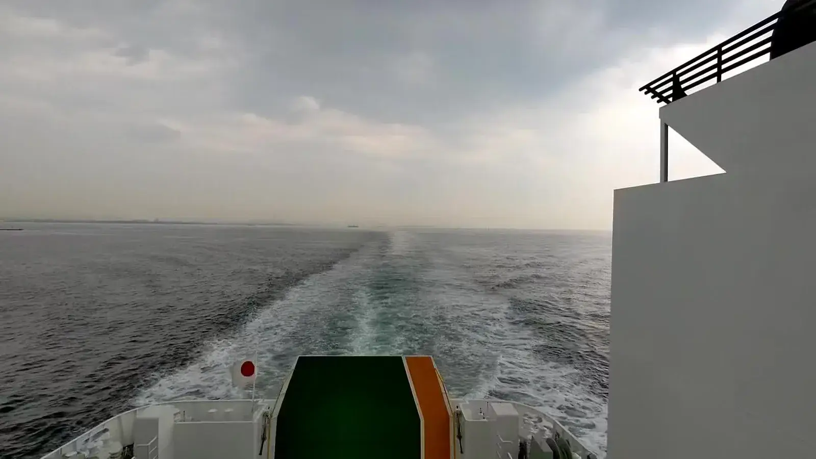A ferry wake stretching into a hazy sea