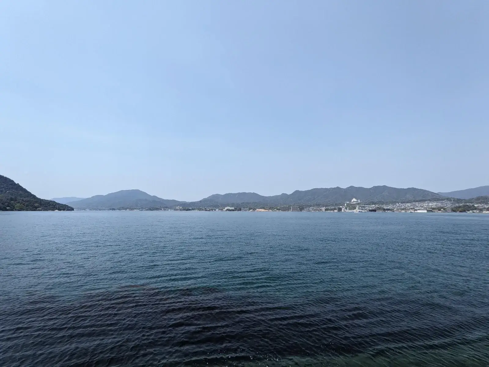 A wide island-dotted bay under pale blue sky
