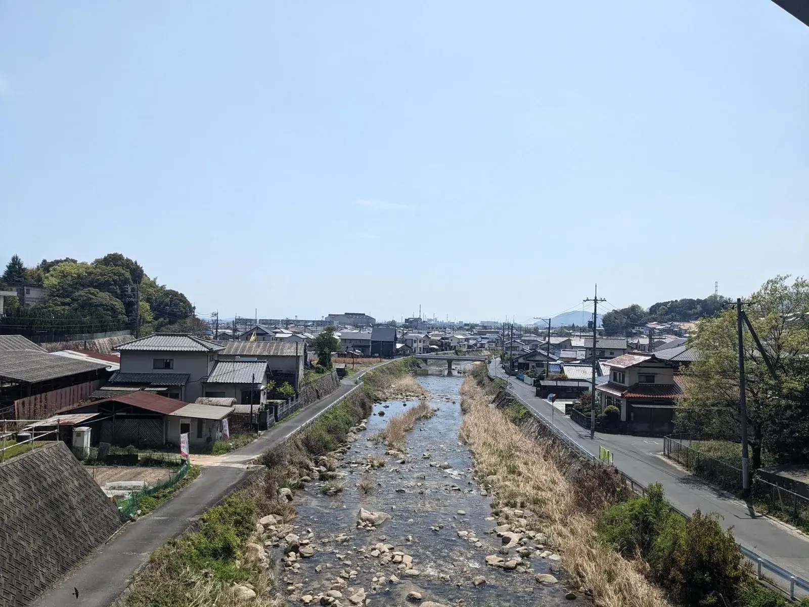 A Japanese town and shallow river viewed from a bridge