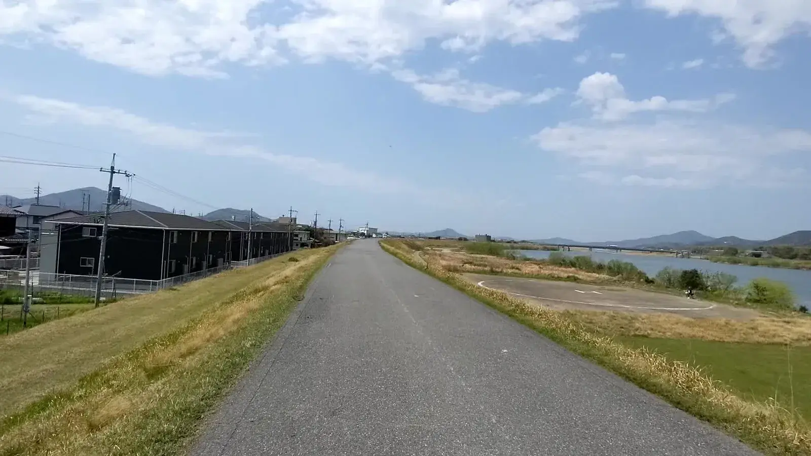 A straight riverside cycle path beneath blue sky