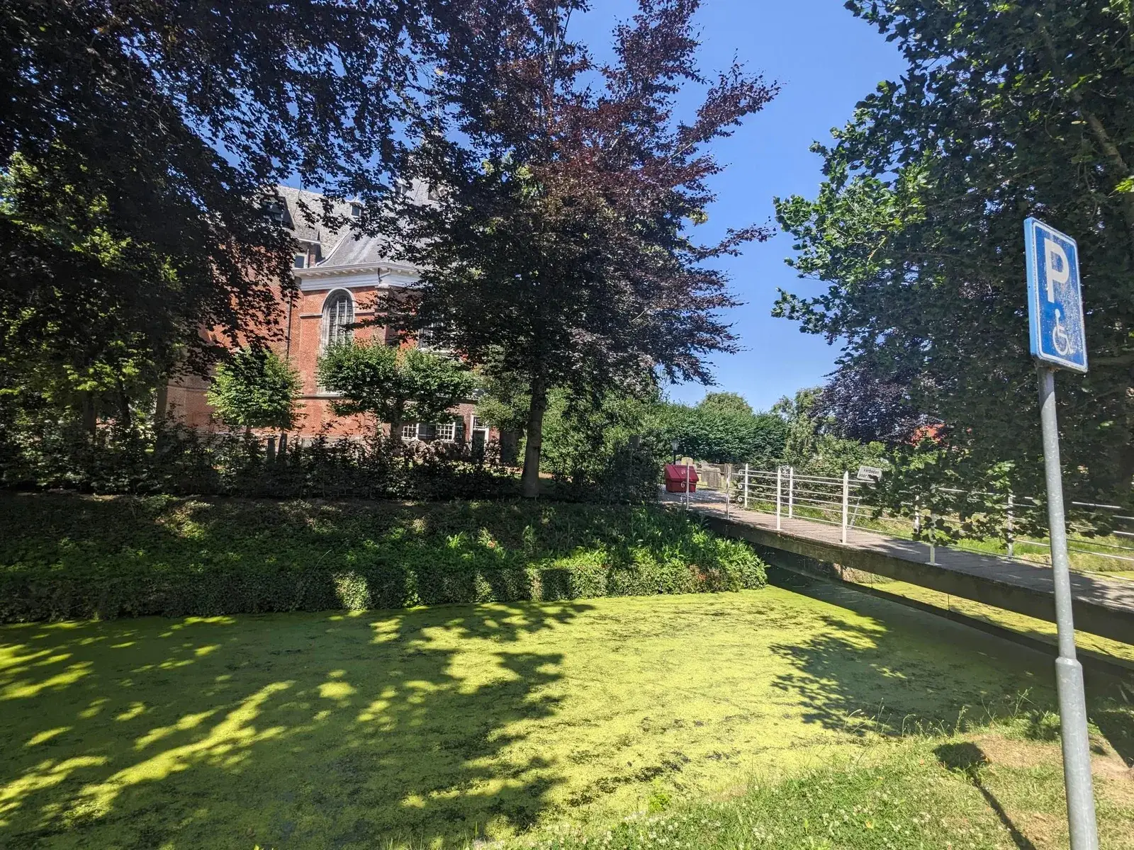 A narrow canal passing gardens and brick houses