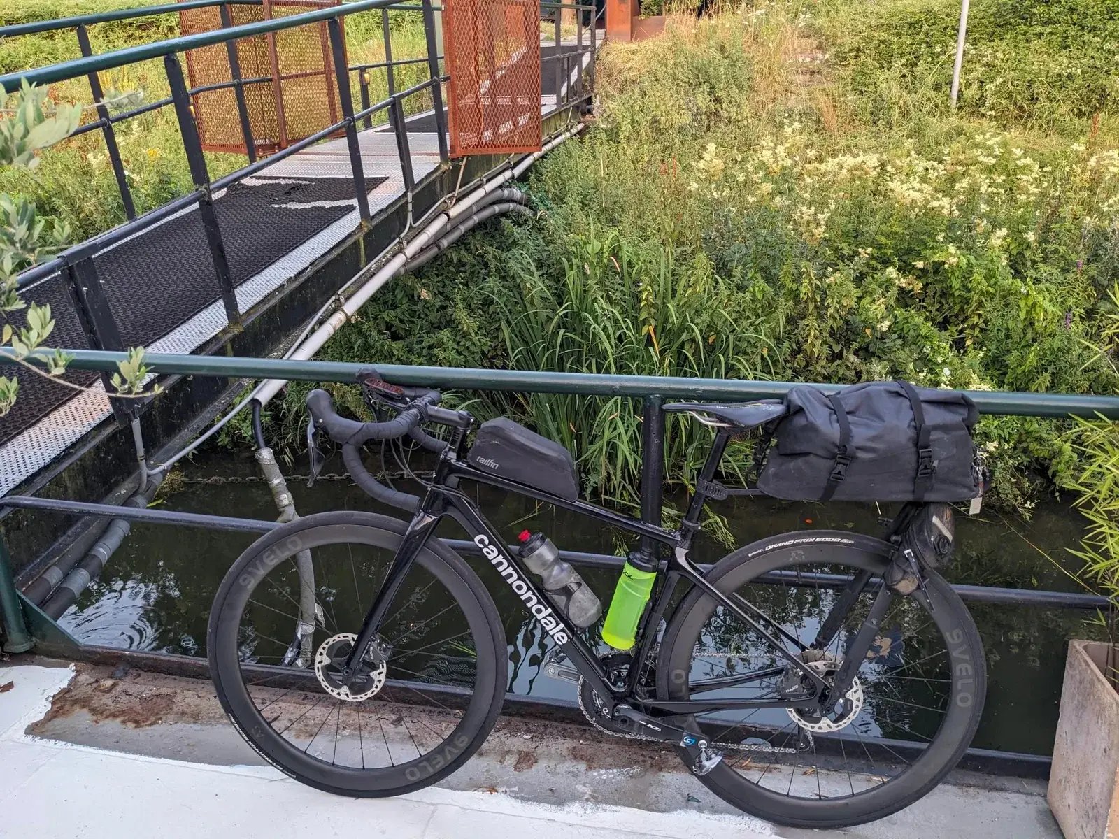 A loaded touring bicycle parked beside a metal footbridge