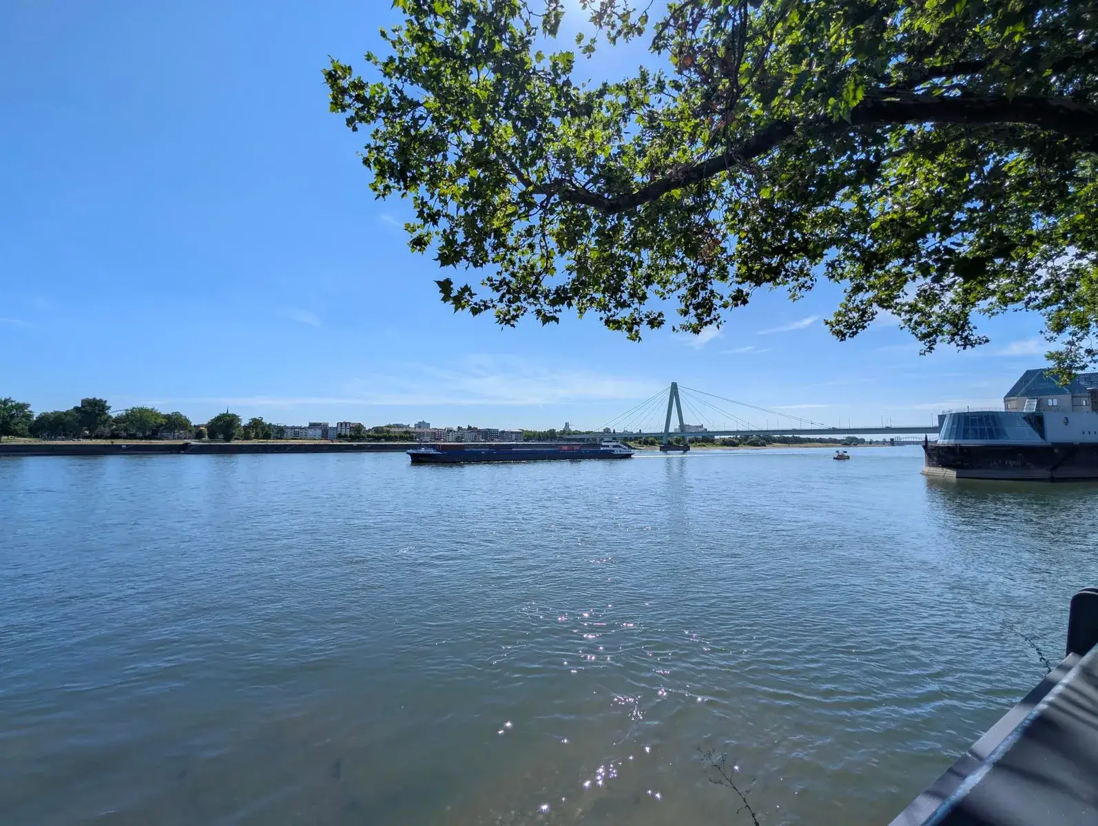 A calm lake crossed by a low bridge beneath blue sky