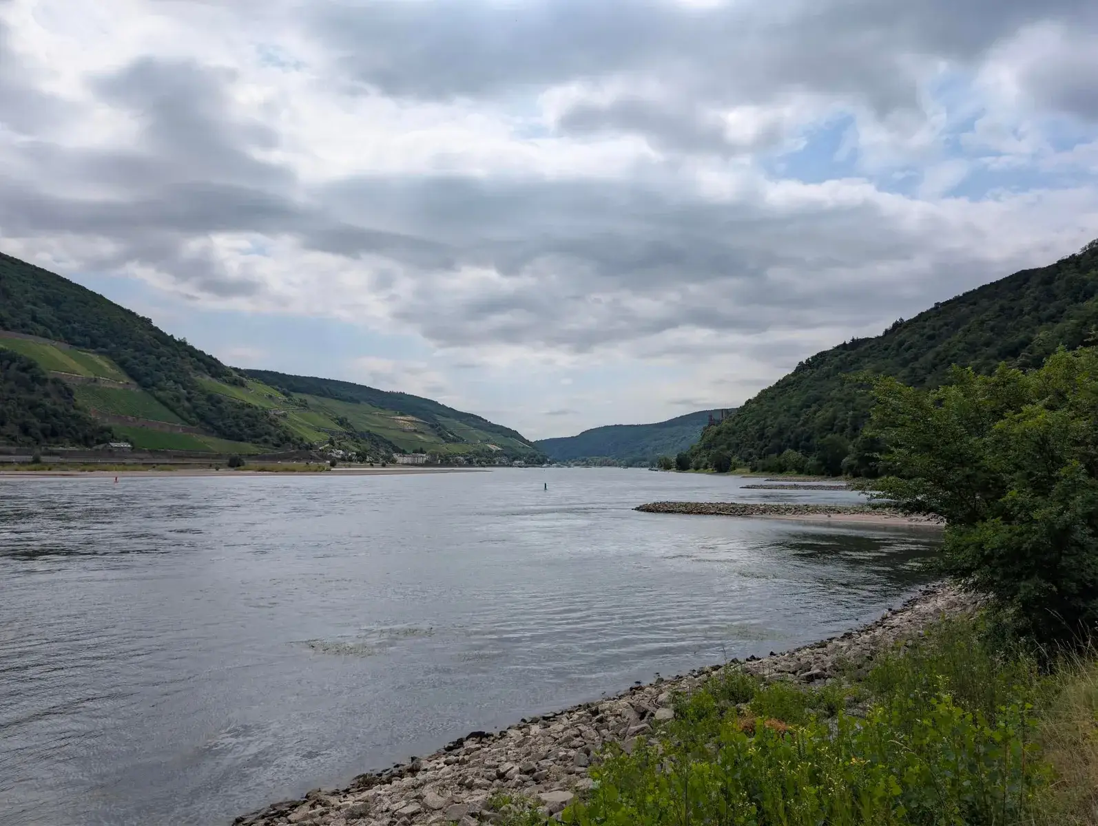 A broad river flowing between steep wooded hills