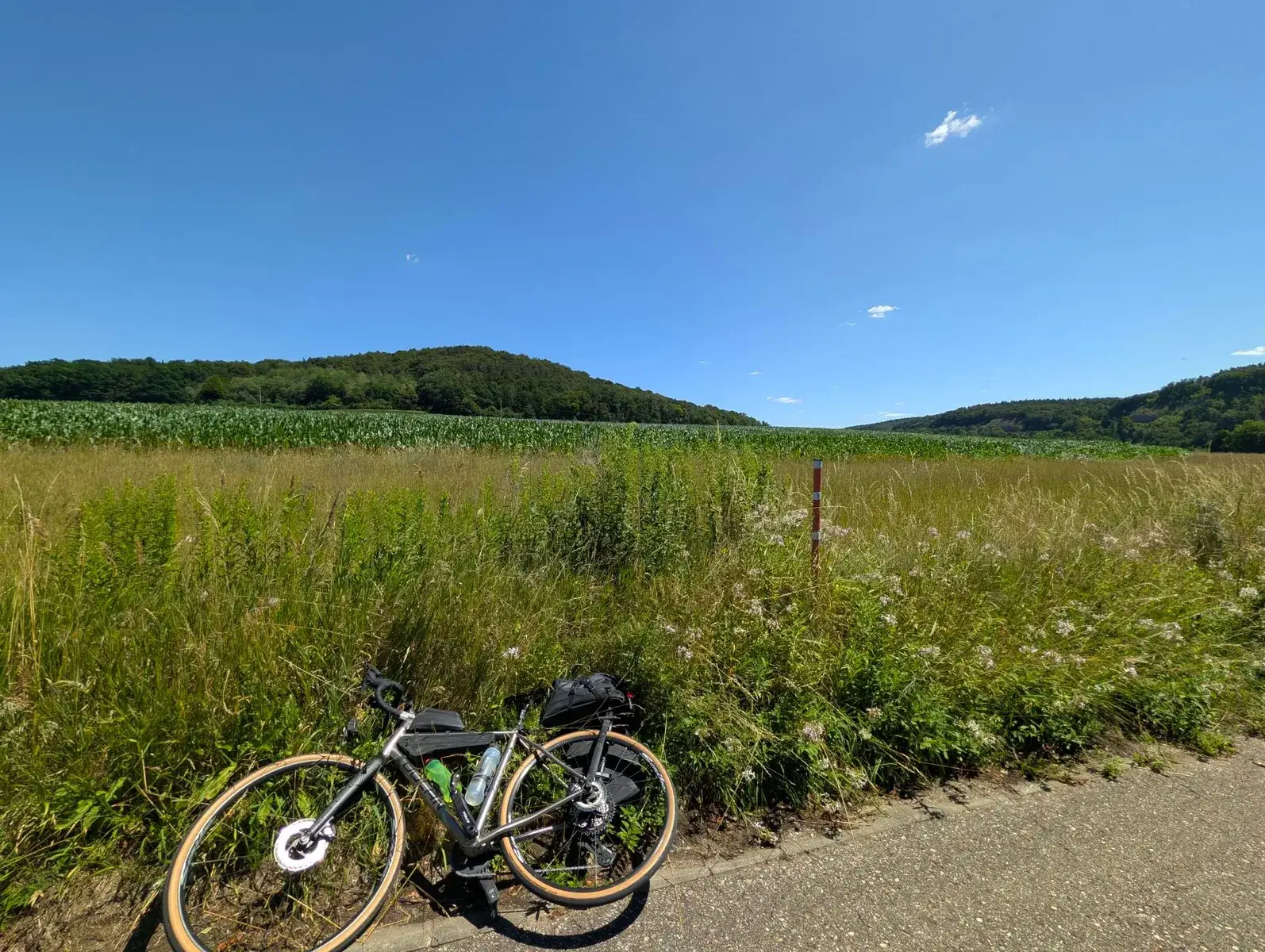 A loaded bicycle beside a wide sunlit field