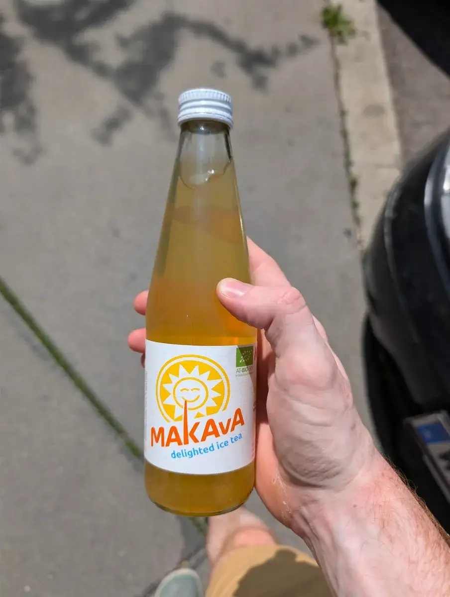 A bottle of orange soft drink held outdoors