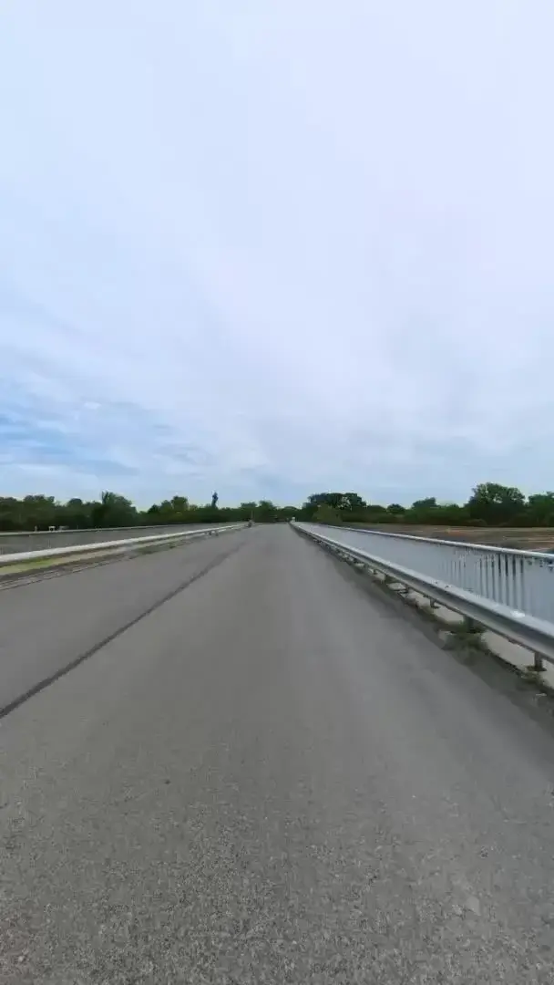 An empty road crossing a long river bridge