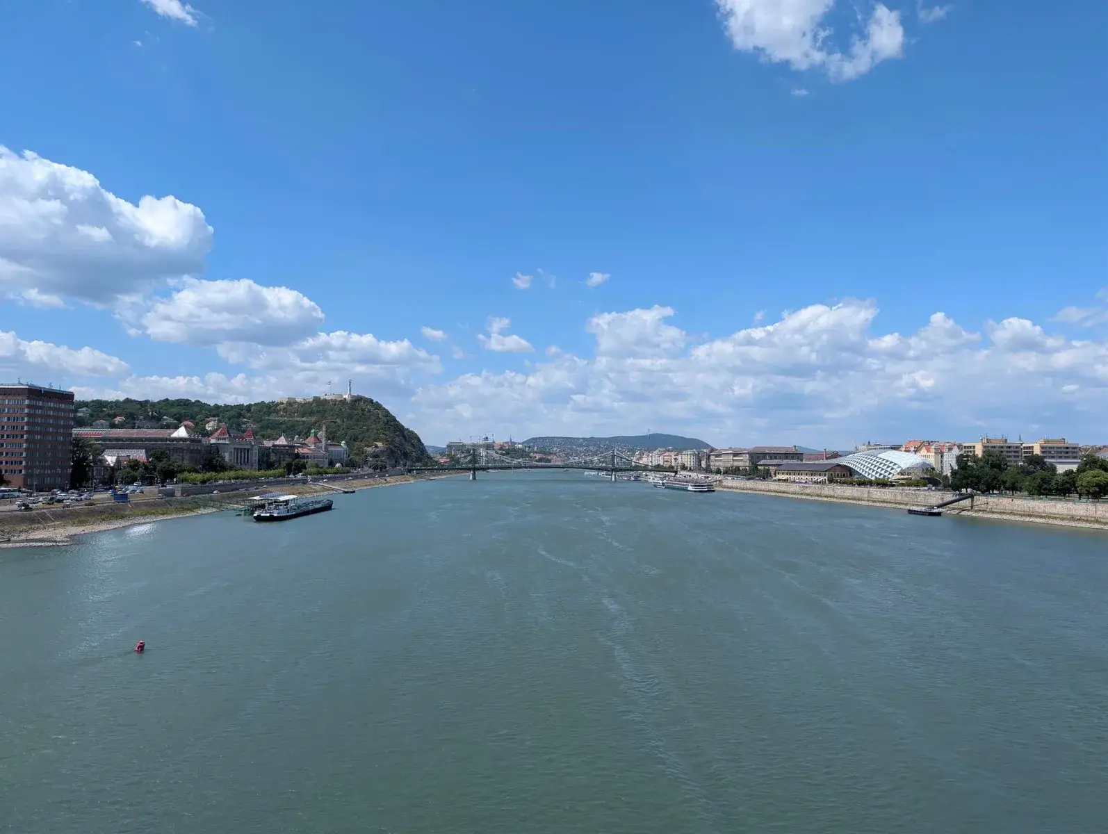 A wide river running through a city beneath bright cloud
