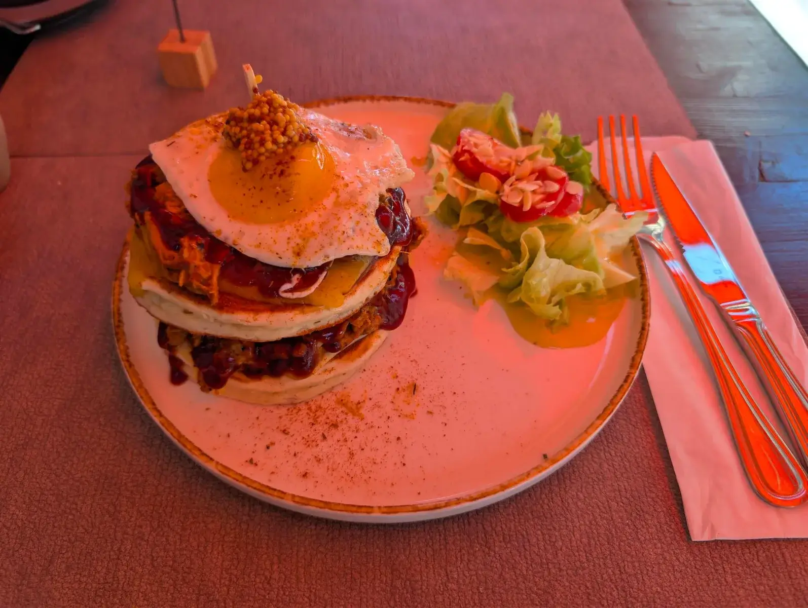 A tall burger and salad on a restaurant table