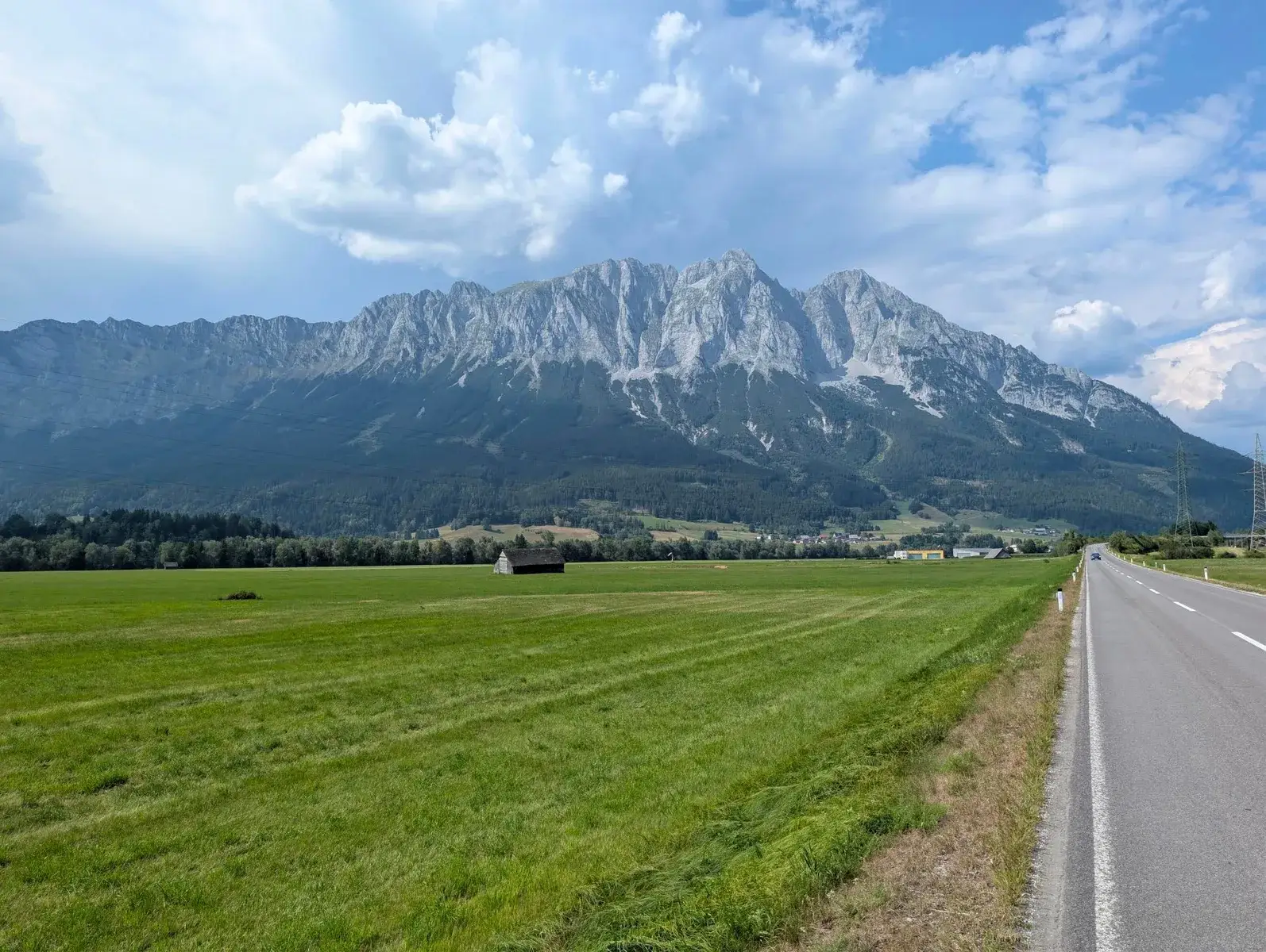 A straight road approaching a dramatic mountain wall