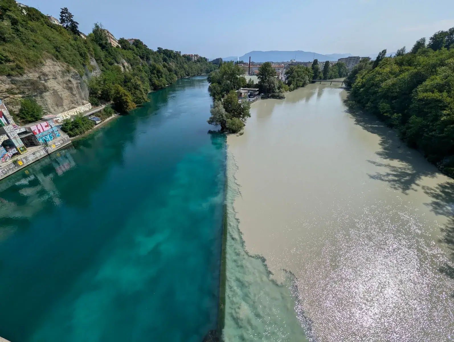 Two differently coloured rivers meeting below a bridge