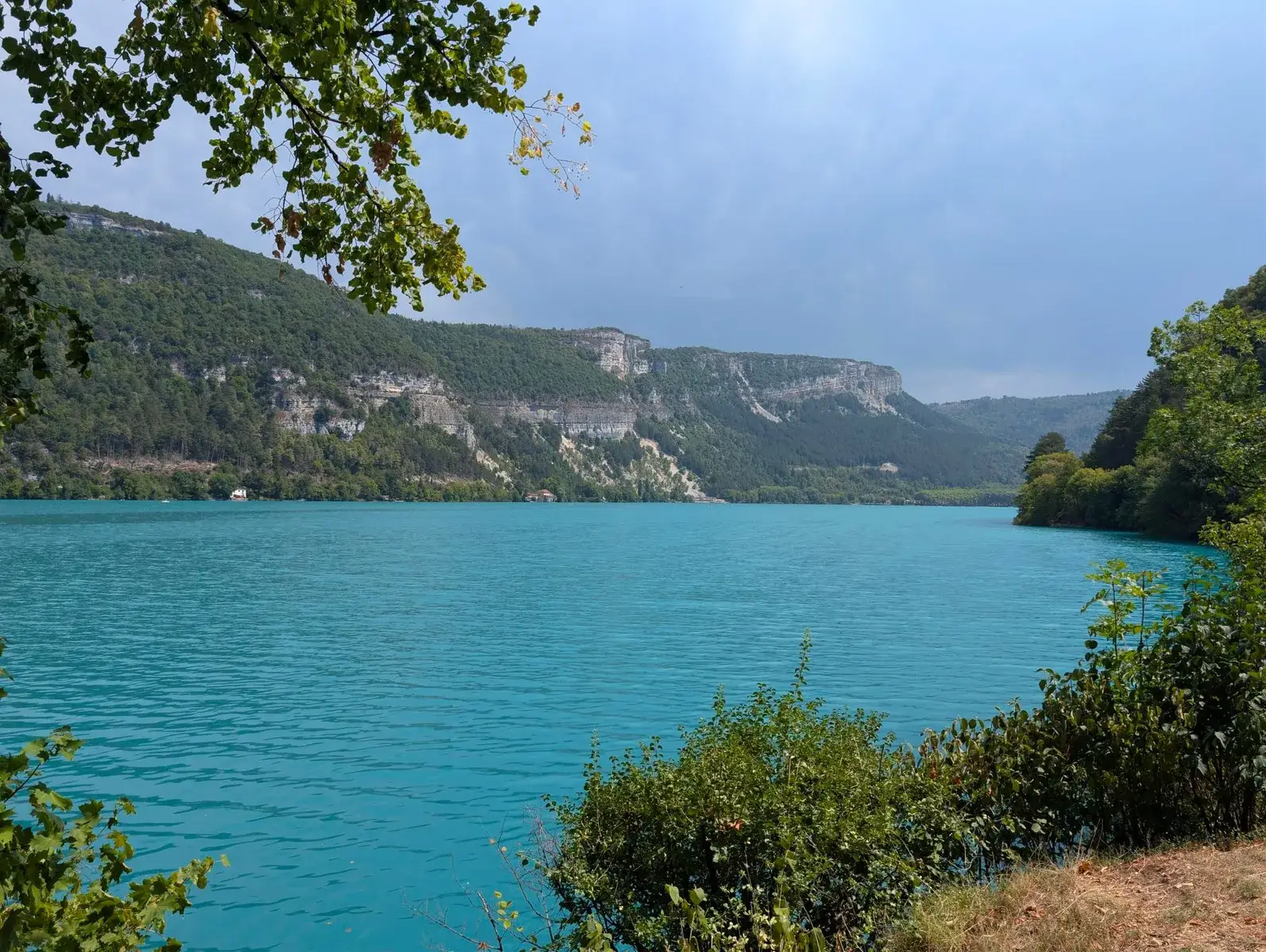 A turquoise alpine lake surrounded by wooded cliffs