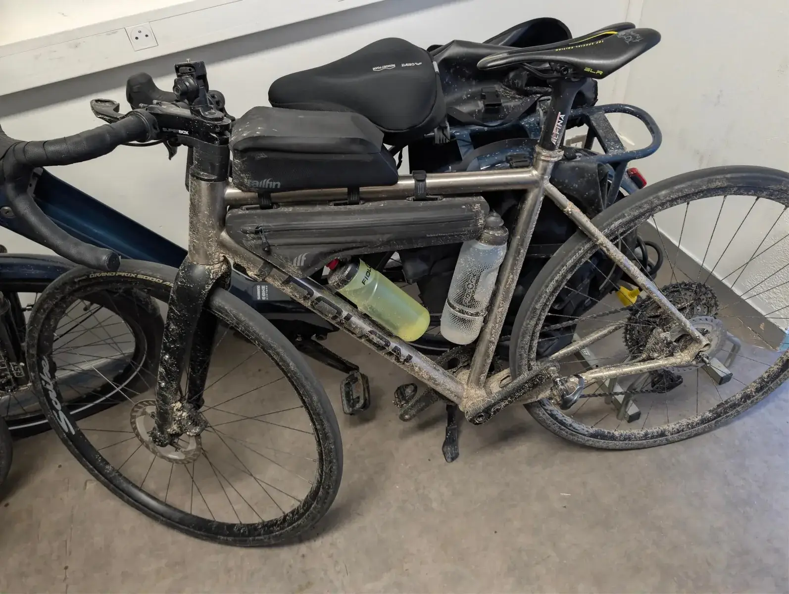A mud-spattered touring bicycle indoors