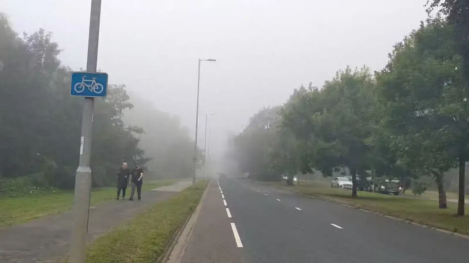 A cycle path disappearing into thick morning mist