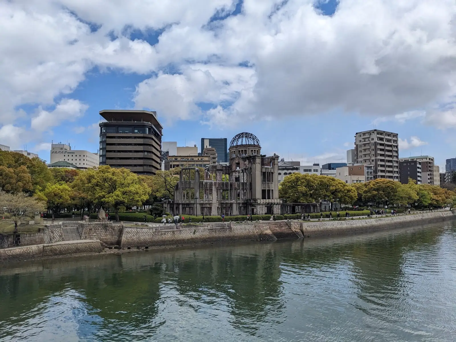 The Atomic Bomb Dome’s skeletal ruins surrounded by modern Hiroshima buildings on the riverbank