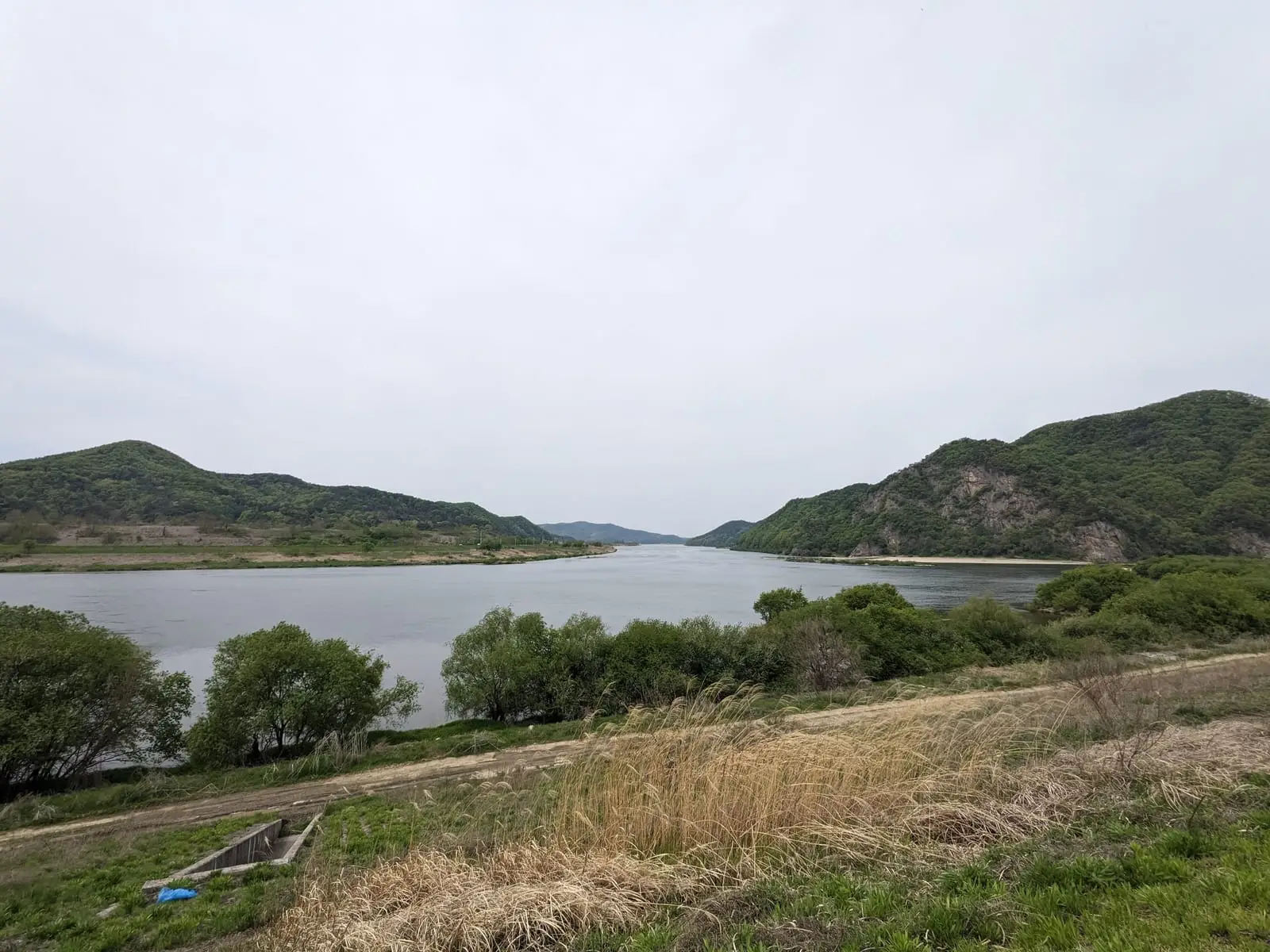 A calm reservoir framed by low hills under an overcast sky