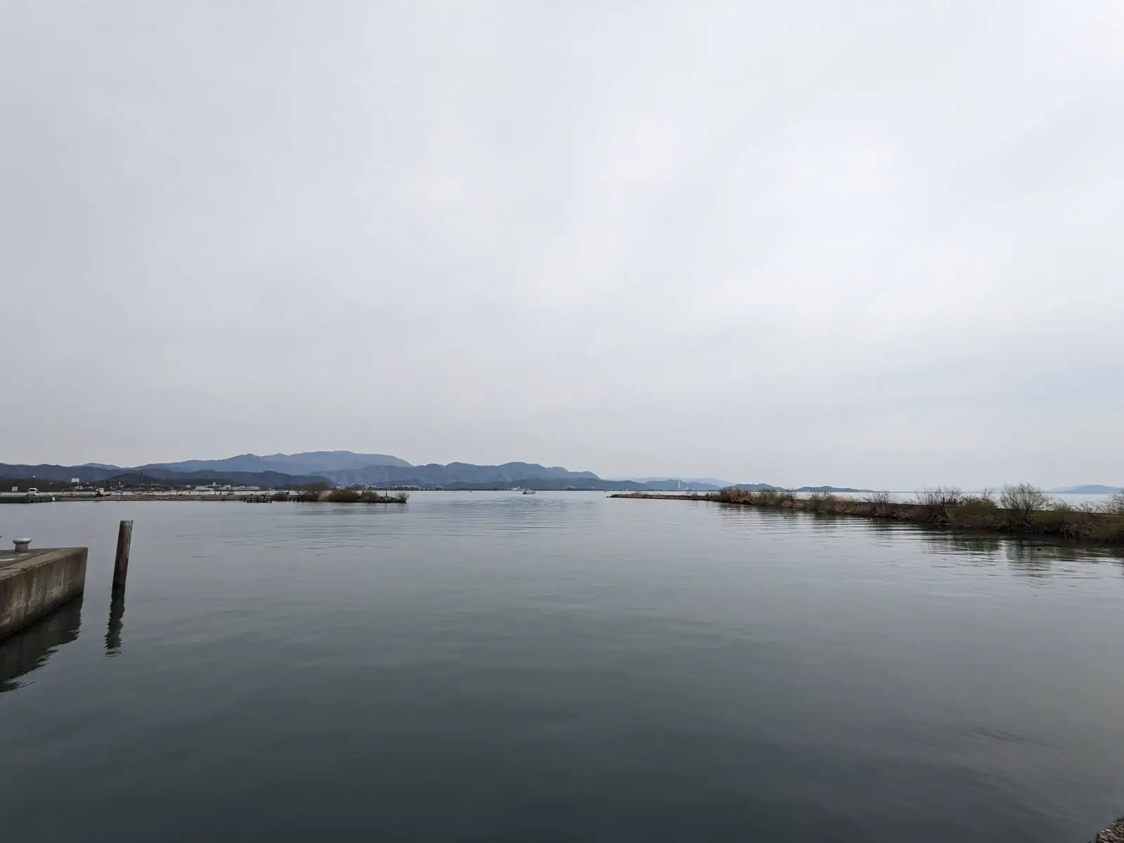 A calm, wide view across Lake Biwa from a jetty, under an overcast sky