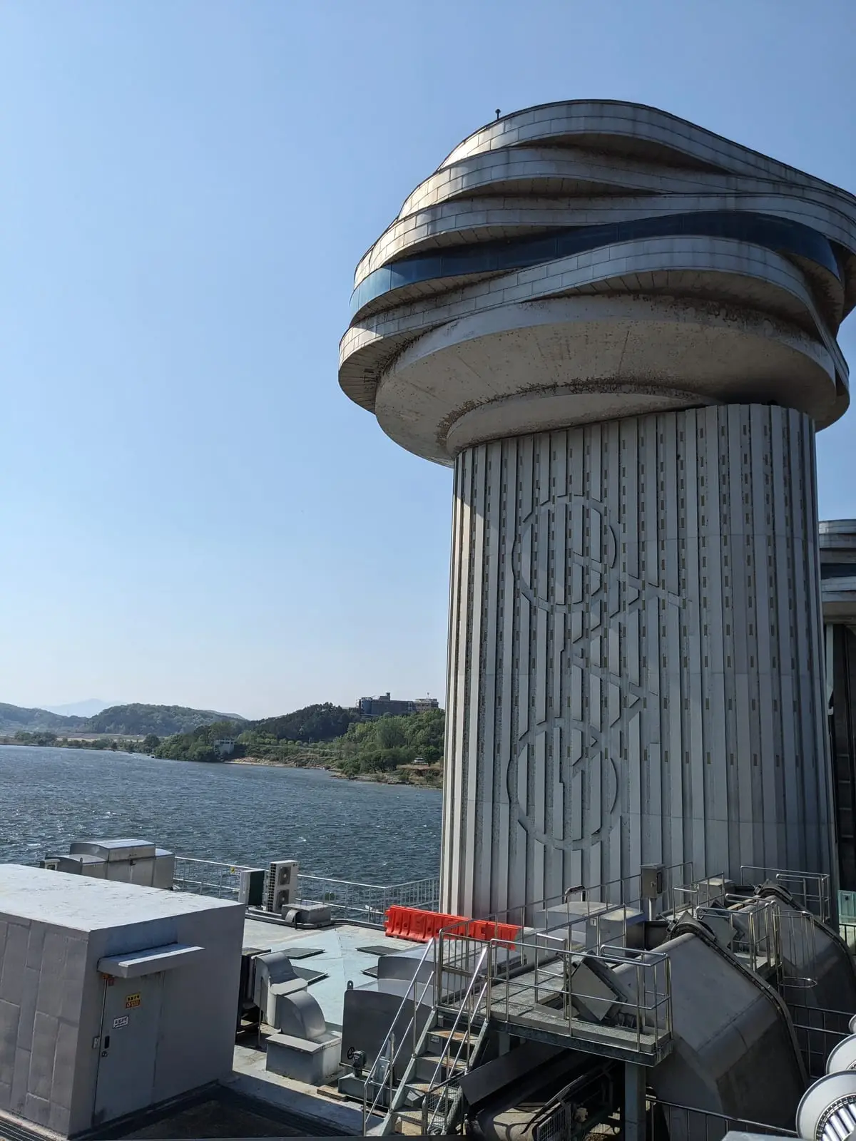 A carved stone pillar beside a lake, part of a bridge or monument