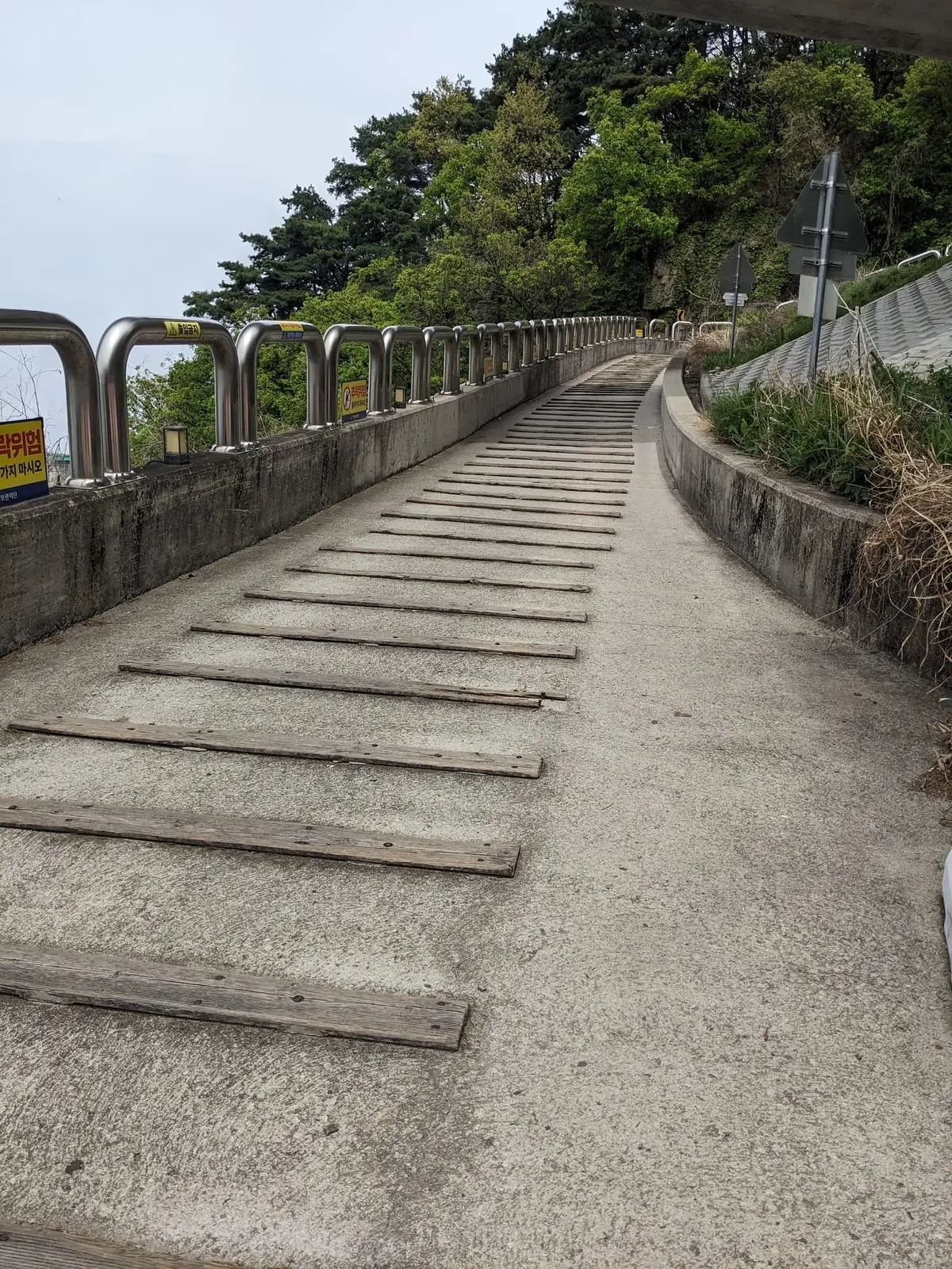 A long flight of concrete steps rising beside a bridge approach