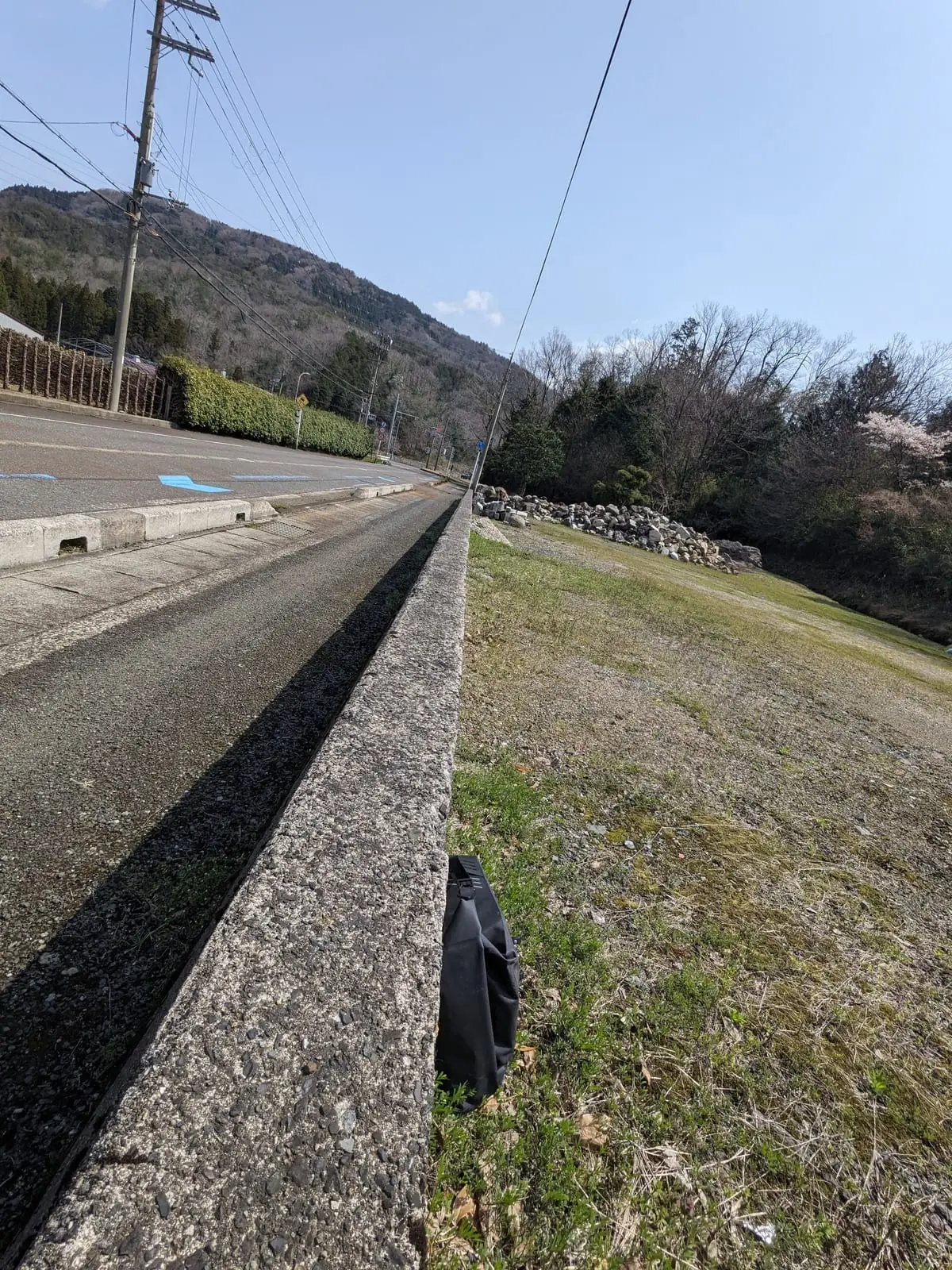 A cycle path running along a low stone wall on a hillside above Lake Biwa