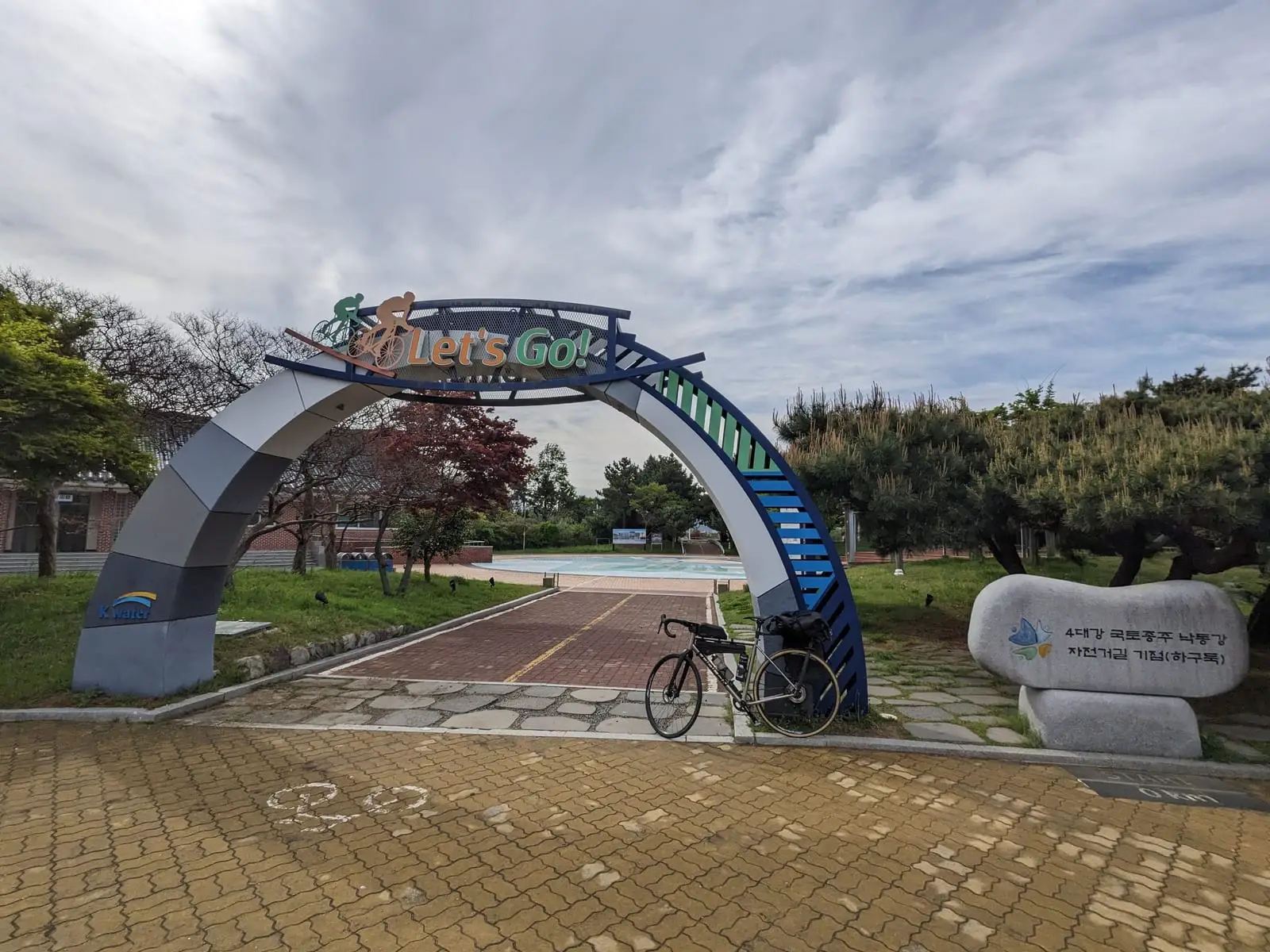 A blue gateway arch marking the start of a cycle route, with a loaded bike parked beside it