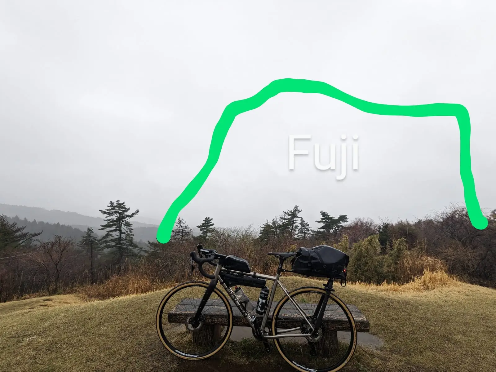 The same cloud-covered viewpoint, with a green line doodled over the photo sketching where Mount Fuji would be
