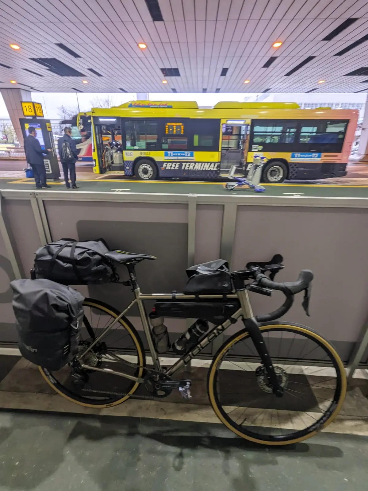 A fully assembled loaded touring bike standing on an airport terminal walkway