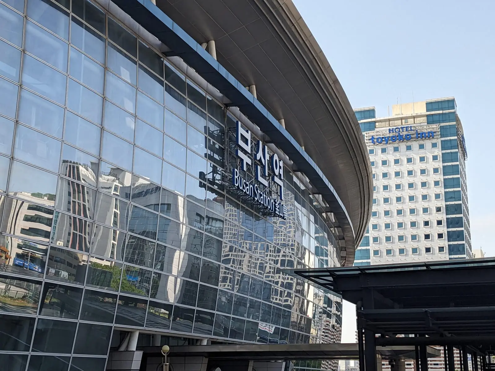 A modern glass-fronted terminal building in Busan with Korean signage across its facade