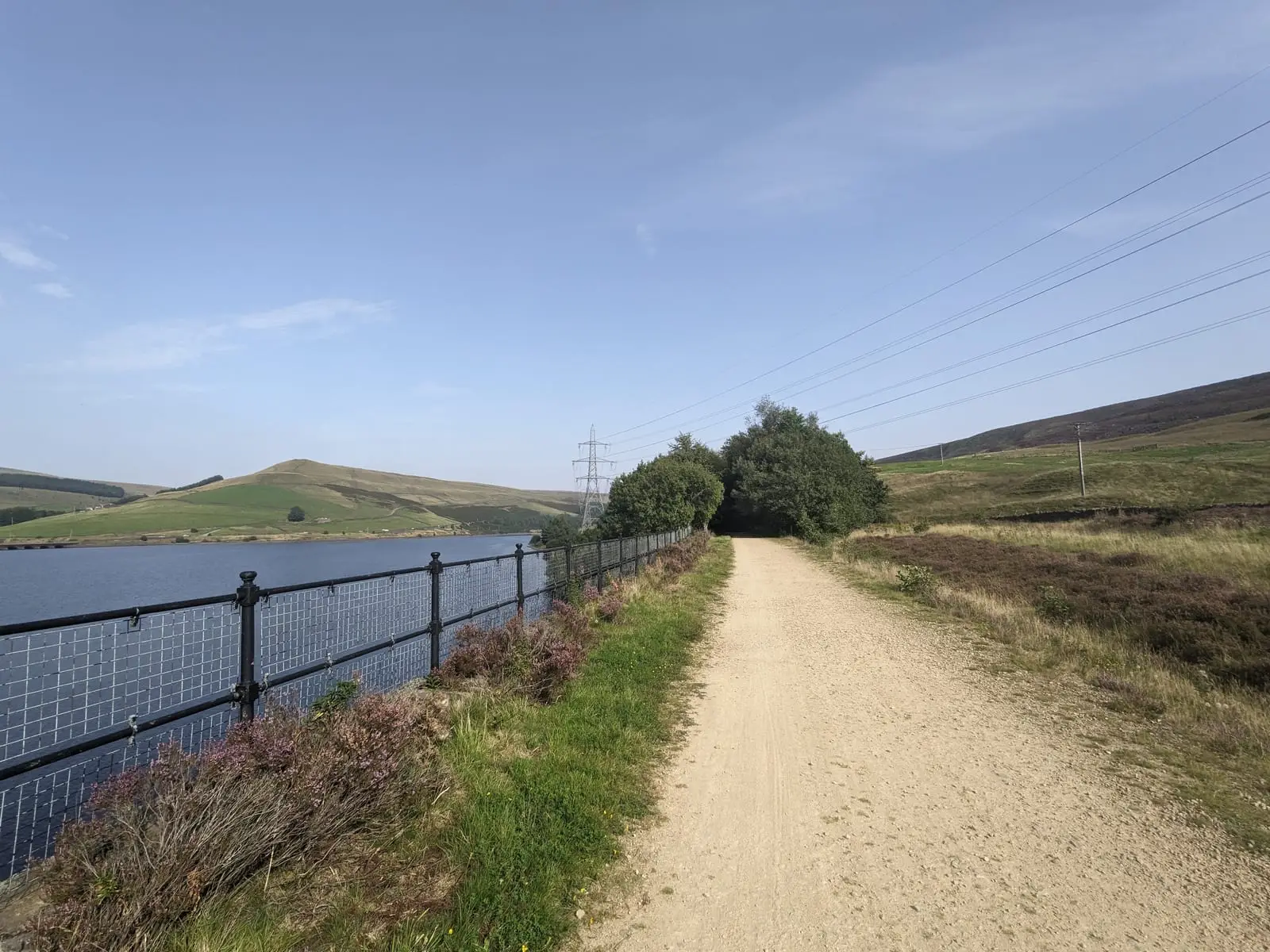 A gravel track running beside a reservoir, with moorland hills beyond