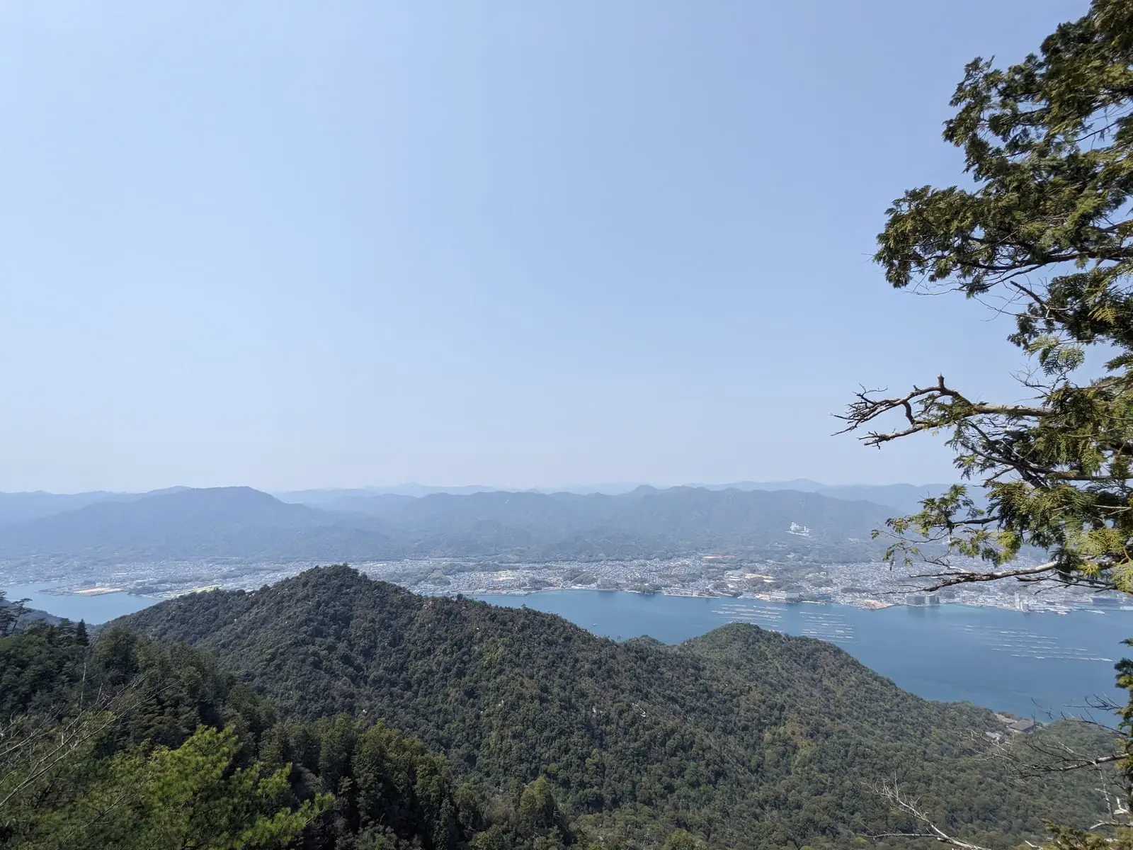 A hazy view over a bay and hills from the hiking trail on Itsukushima