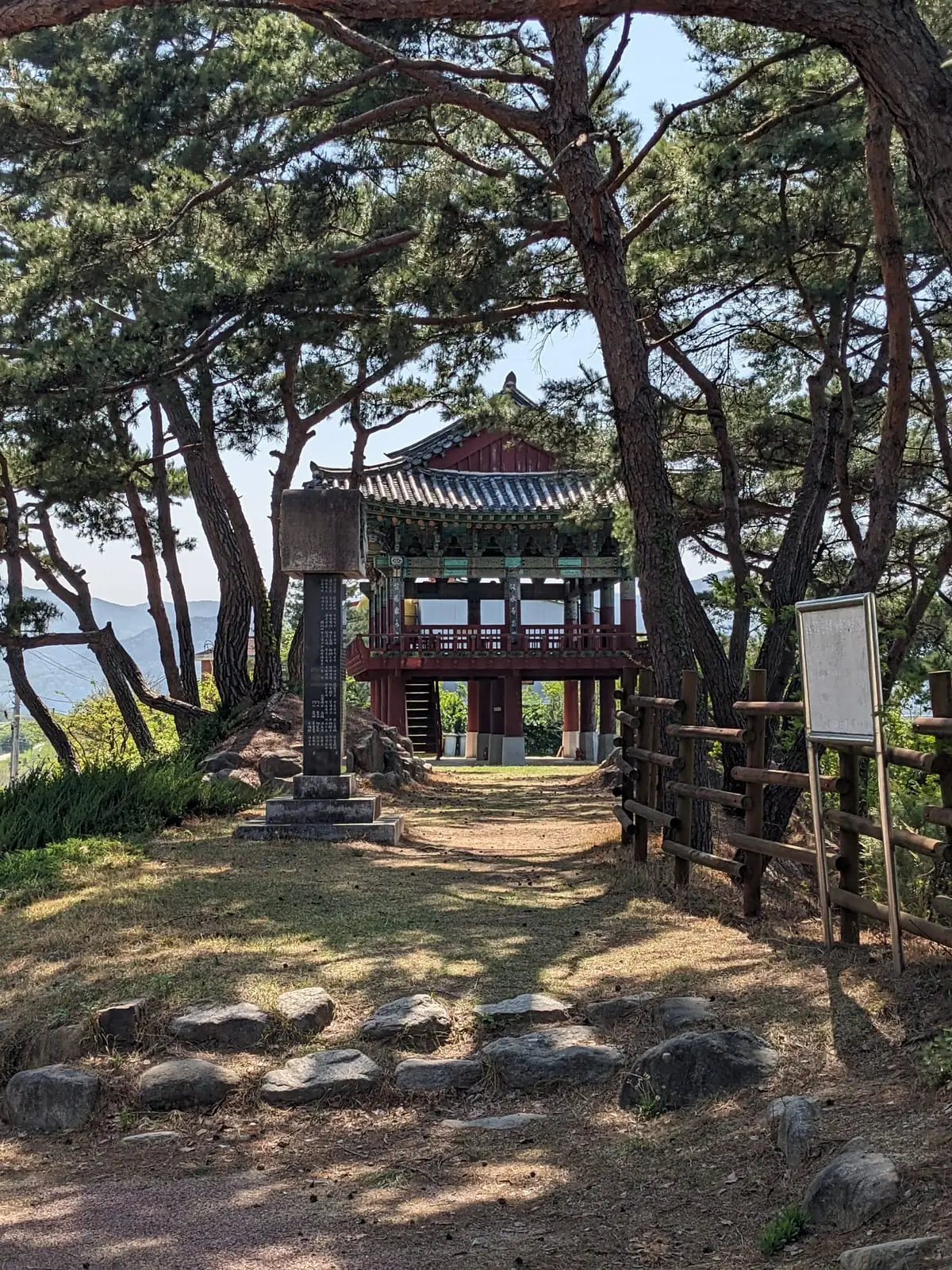 A traditional Korean temple pavilion with an upturned tiled roof among pine trees