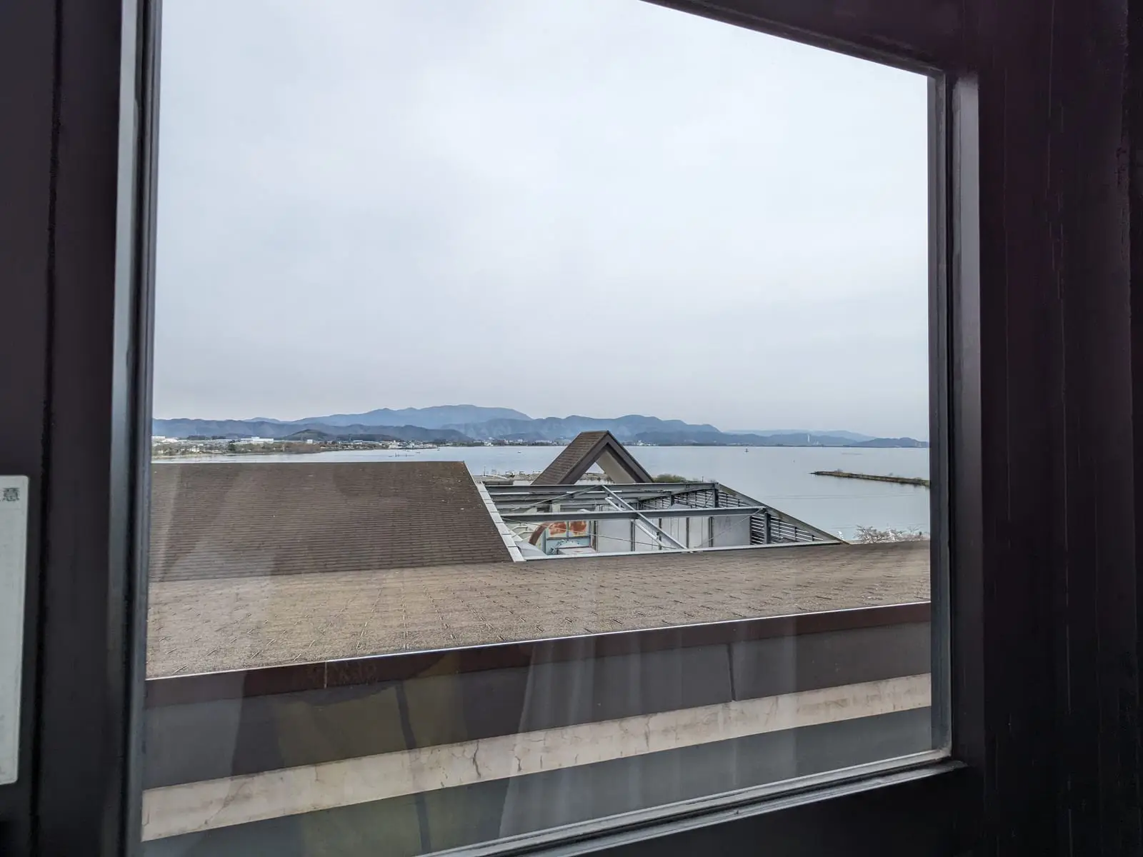 Lake Biwa seen through a hotel room window, with faint reflections visible in the glass