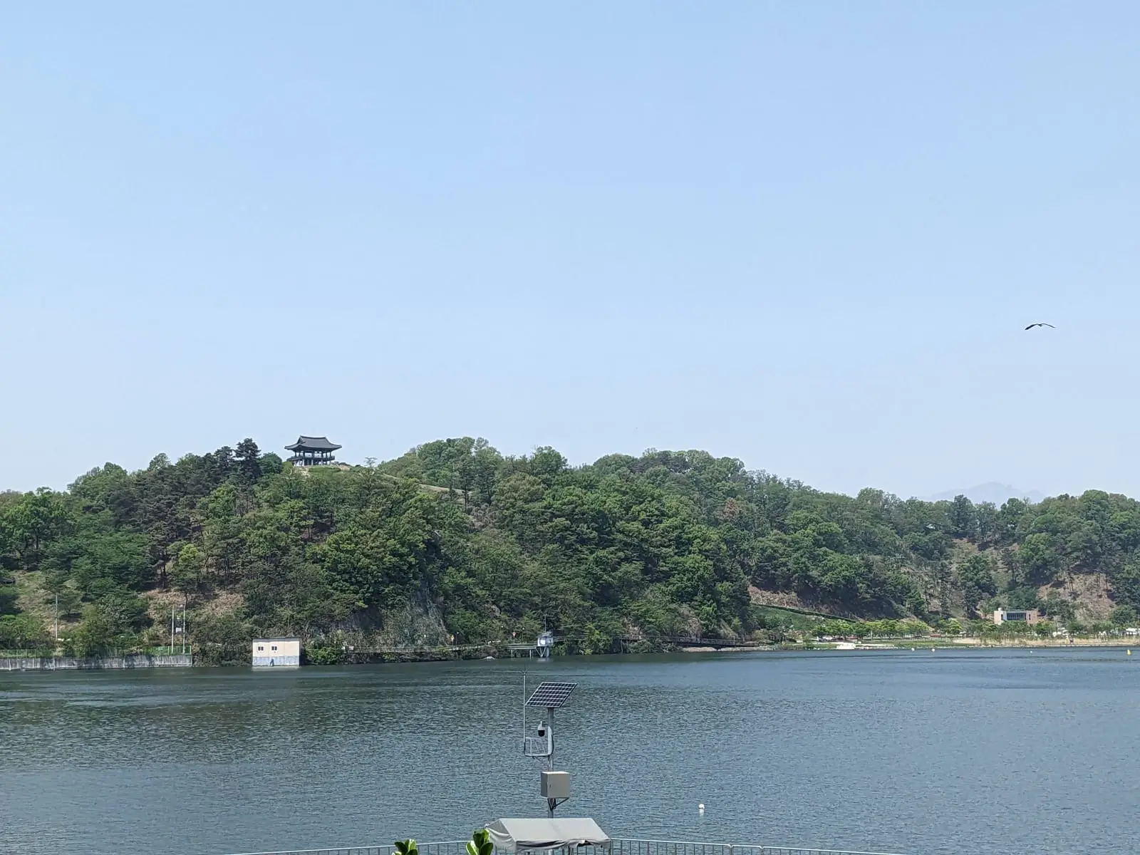 A lake view with a small pagoda-roofed temple building among trees on the far shore