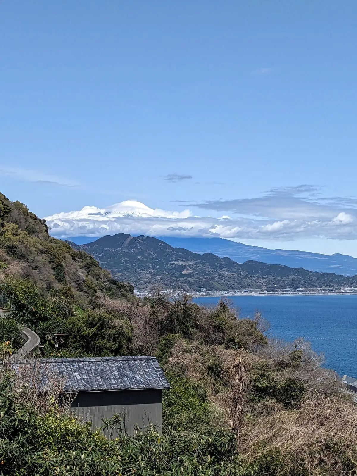 Mount Fuji's snow-capped peak rising above the hills along the coastline