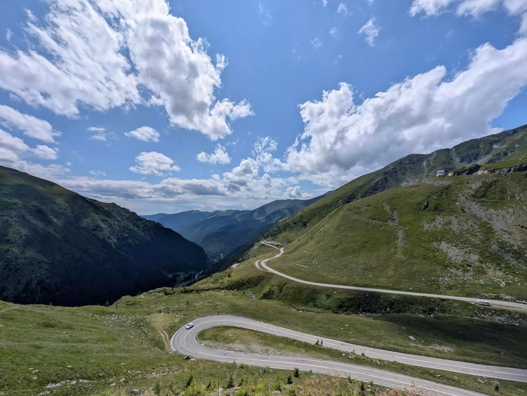 Road switchbacks climbing a green mountain valley
