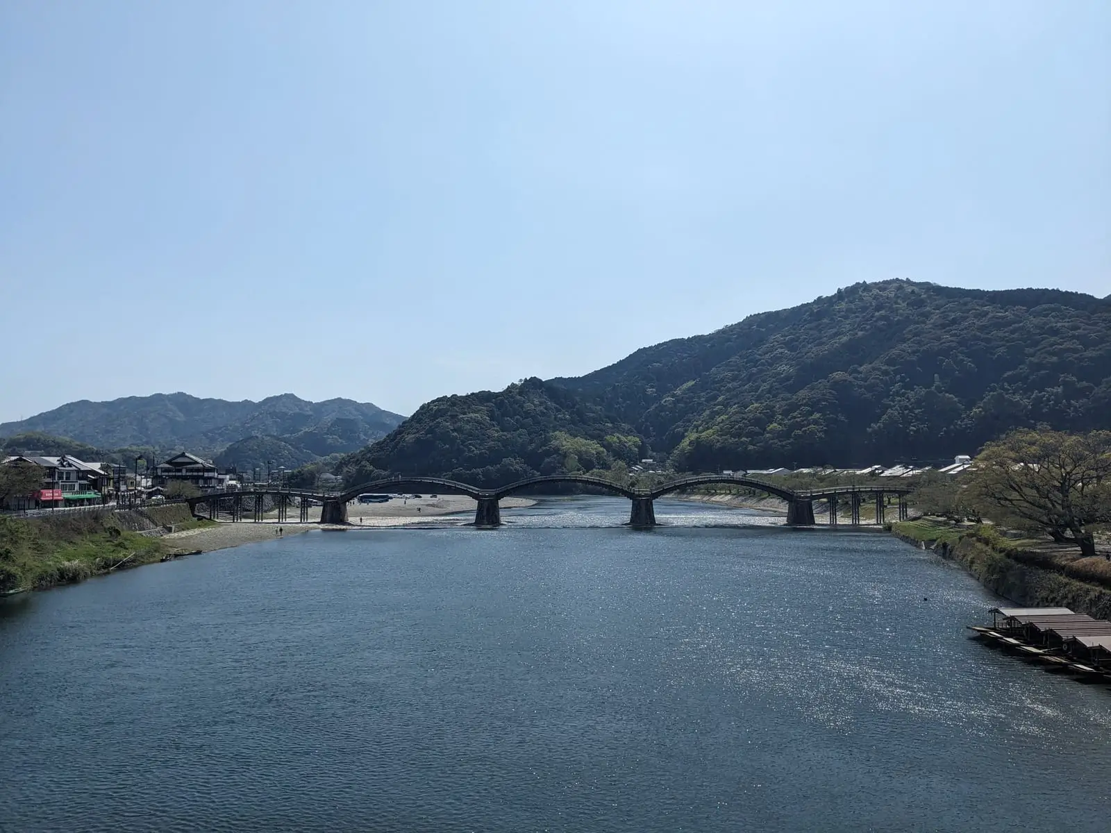 The multi-arched wooden Kintai Bridge crossing a wide river, with hills in the background
