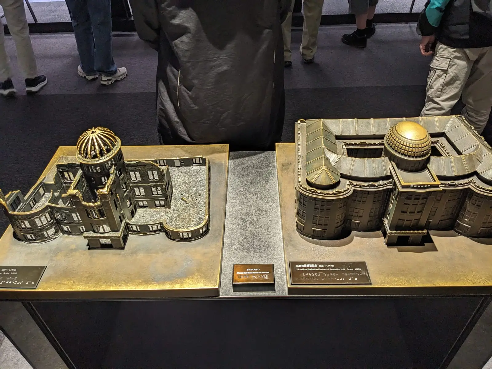 Small architectural models of Hiroshima buildings displayed in the Peace Memorial Museum, with an information plaque in front