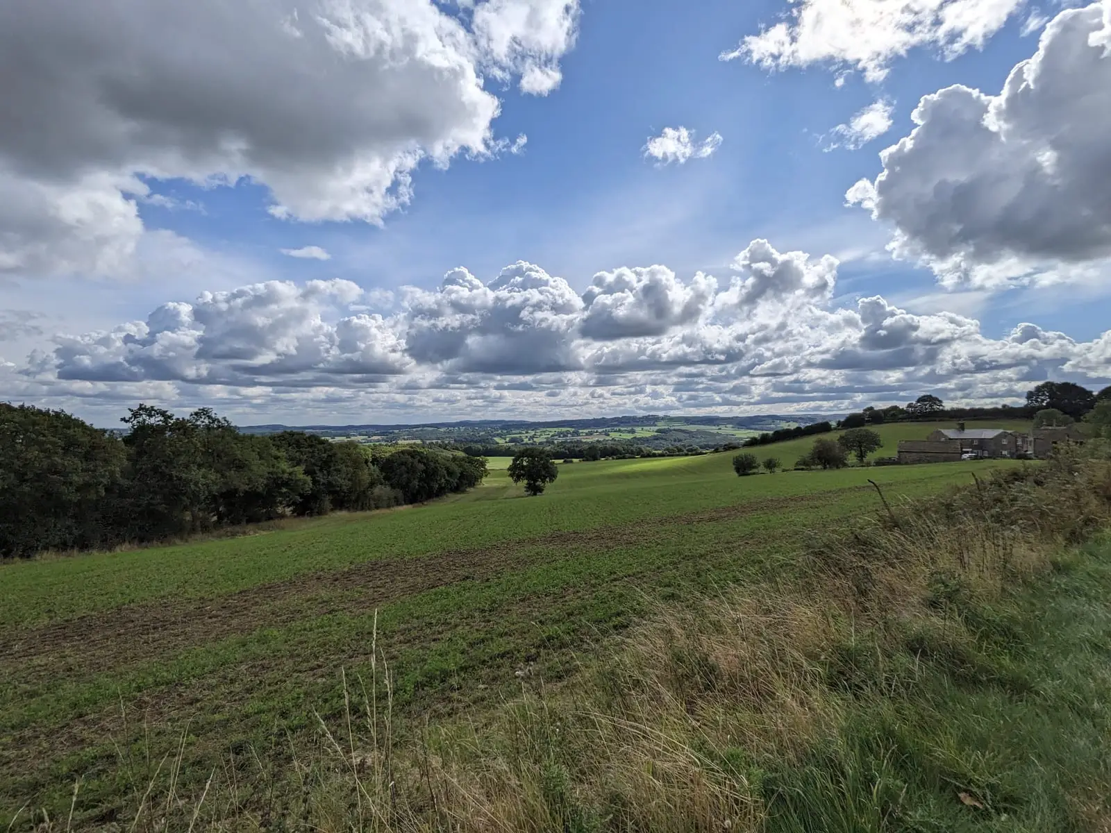 Green hills and fields beneath heavy clouds in the Peak District