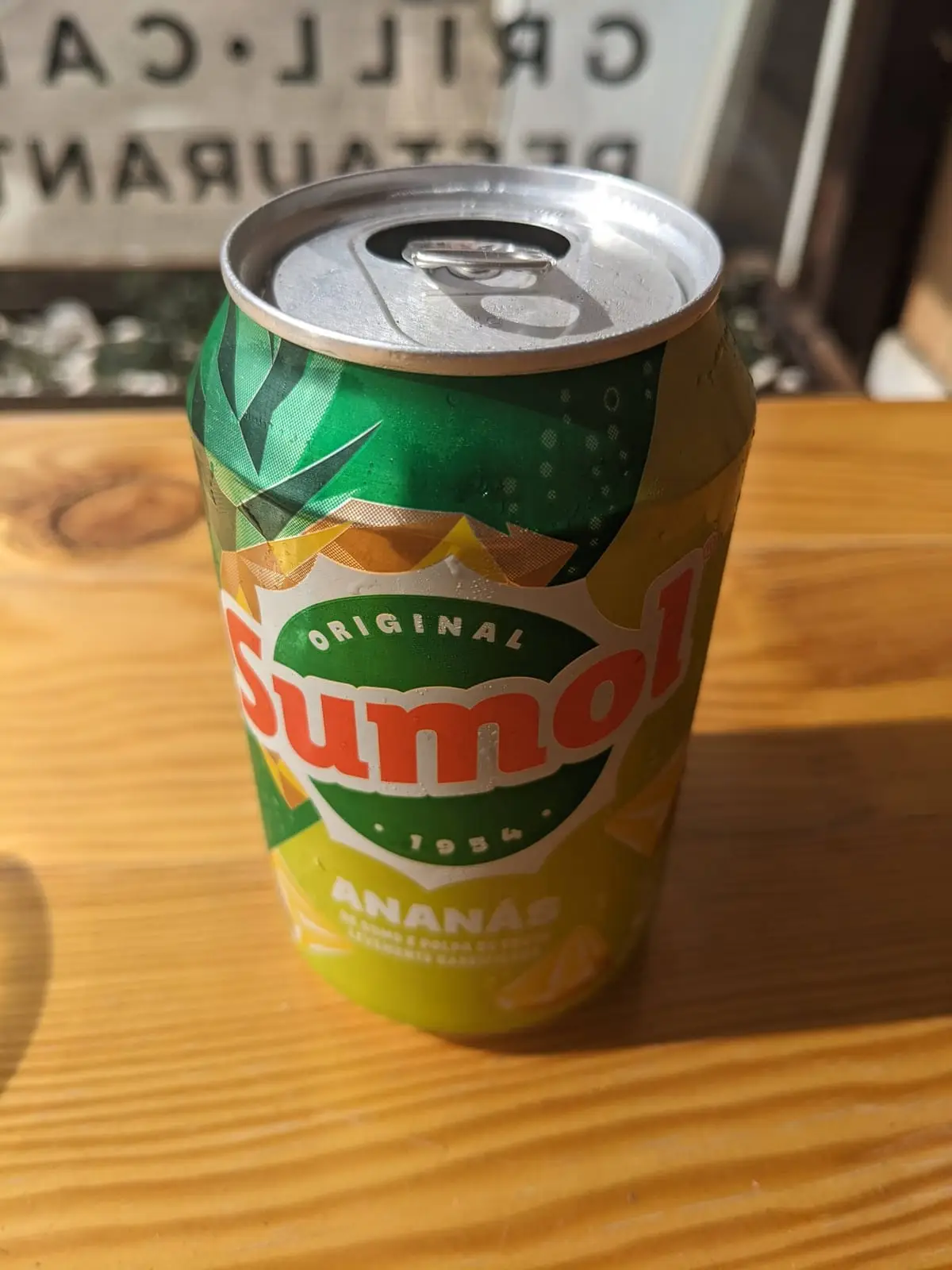 A cold can of pineapple Sumol on a wooden table