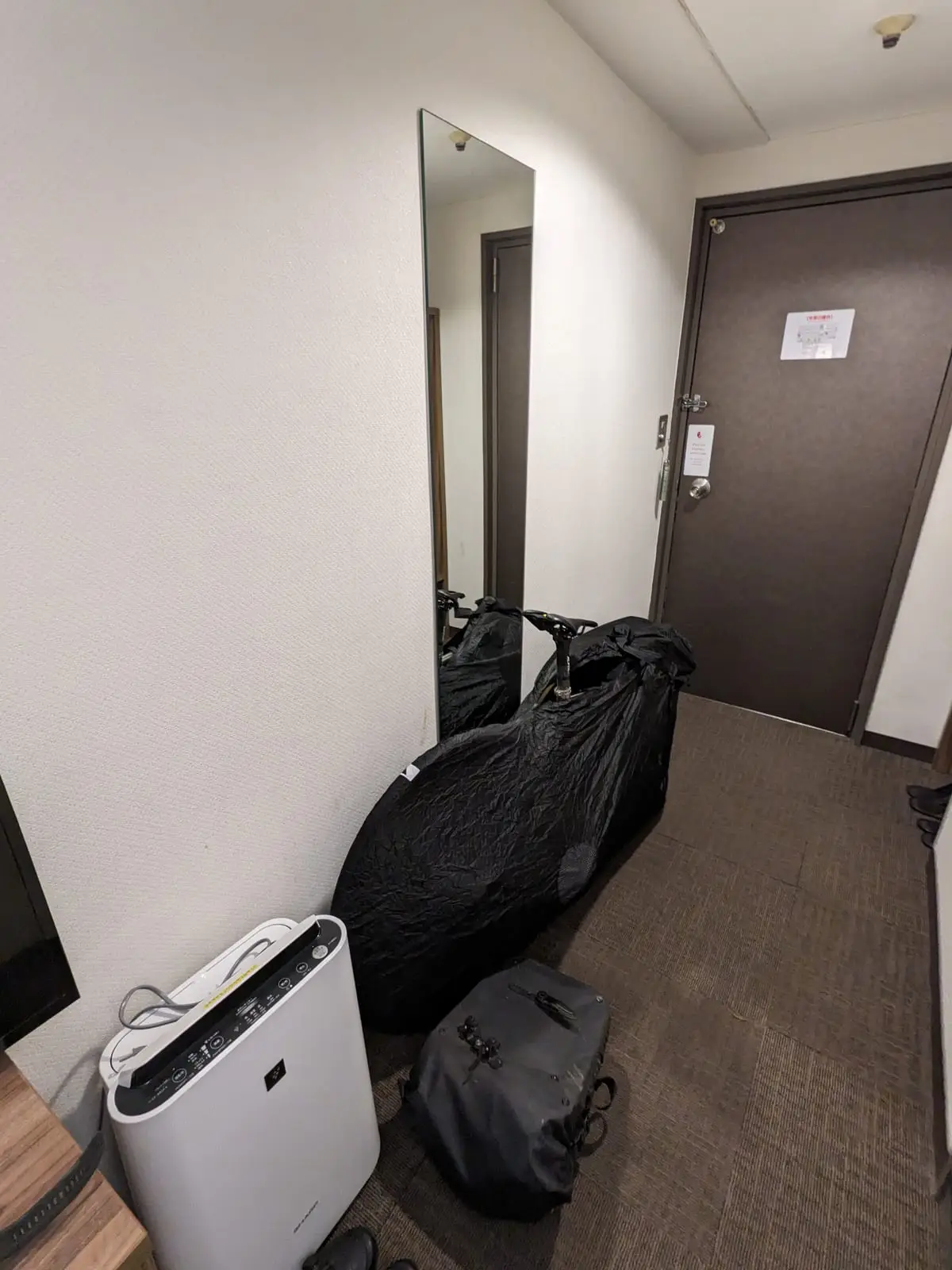 A black rinko travel bag for the bike standing packed in a hotel corridor