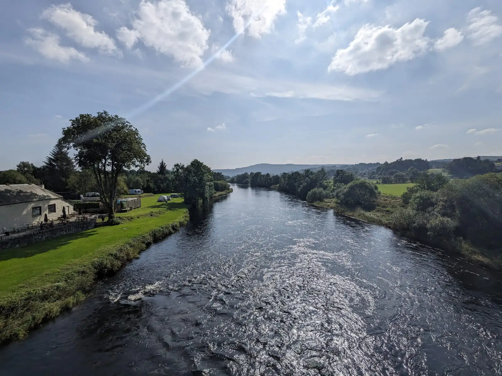 A broad river winding through green countryside beneath a bright sky