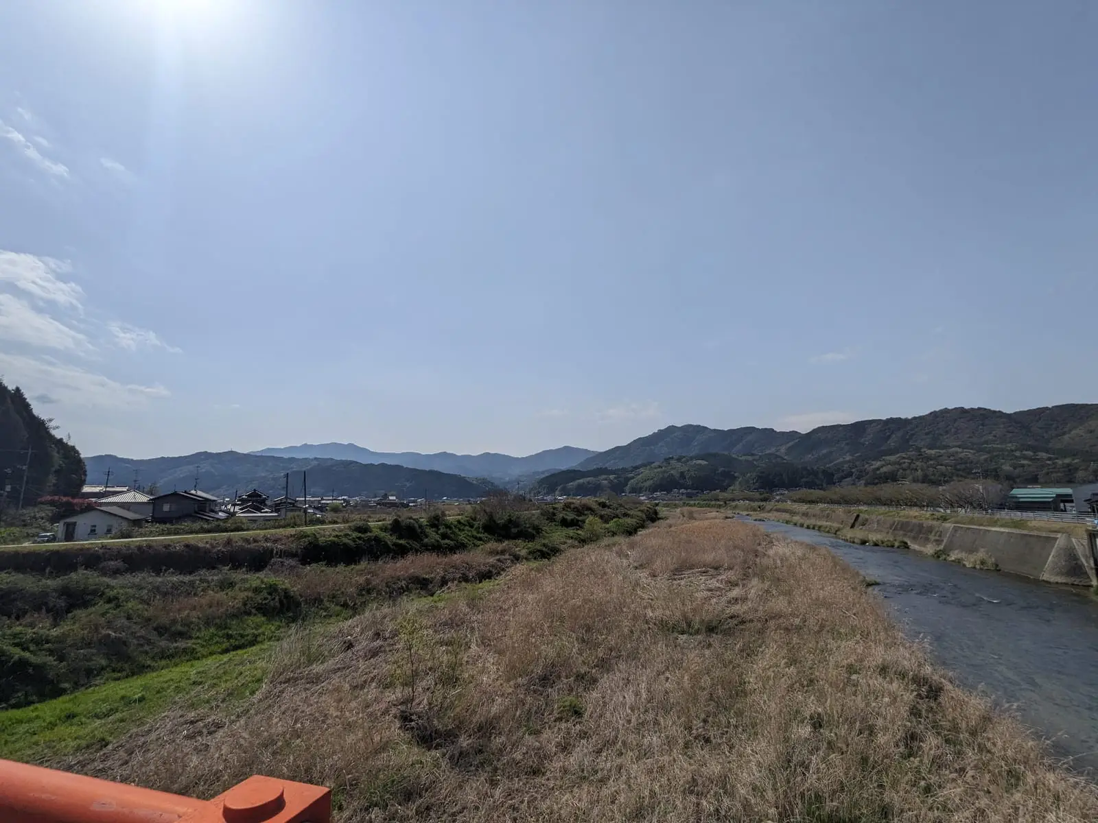 A river valley stretching toward hazy hills under a bright midday sun