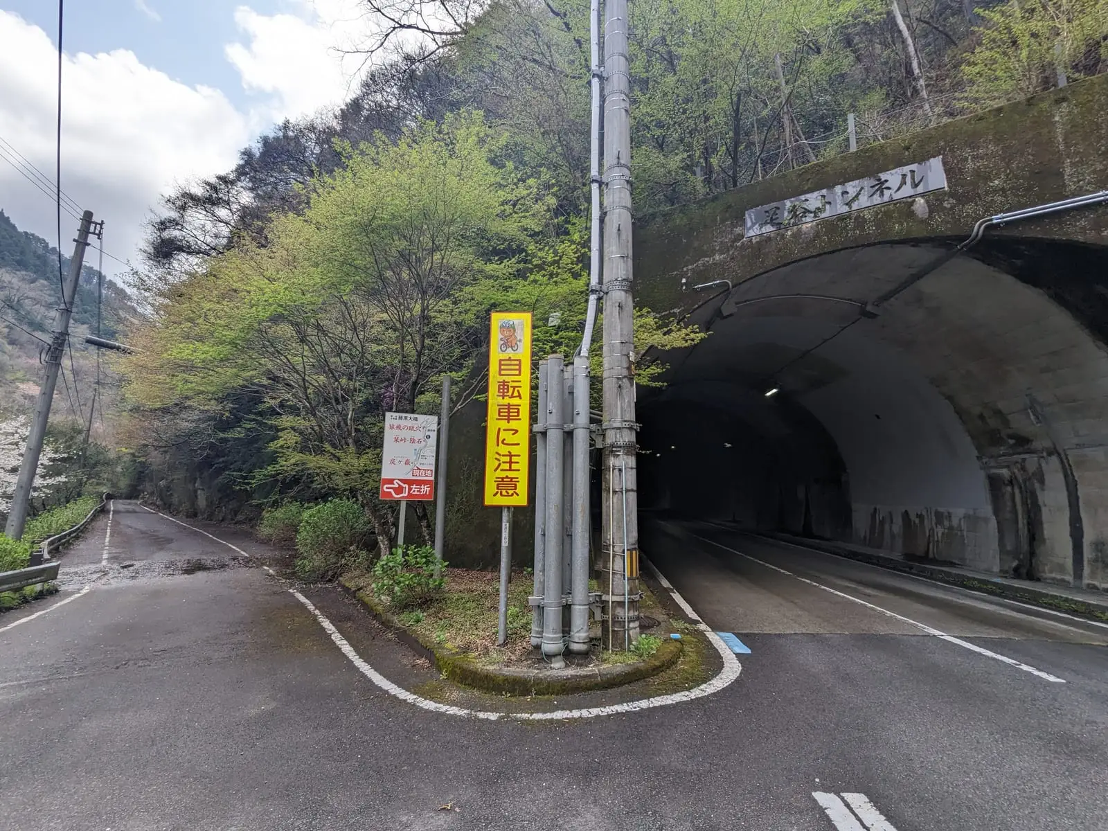 A road junction with warning signs, showing a tunnel entrance off to one side that can be avoided