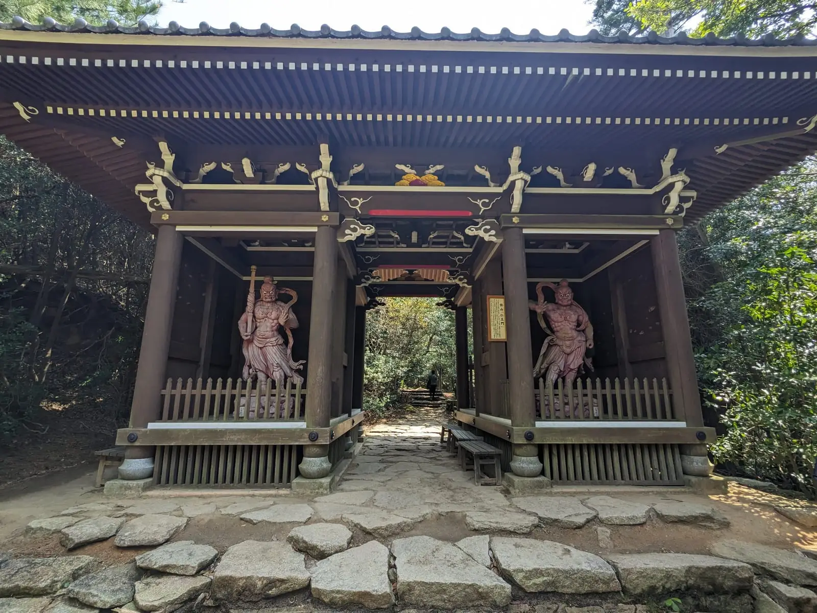 An ornate shrine building with two guardian statues flanking the entrance