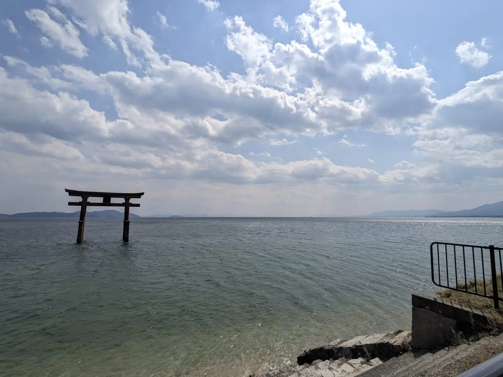 A small torii gate standing in the water near the shore of Lake Biwa