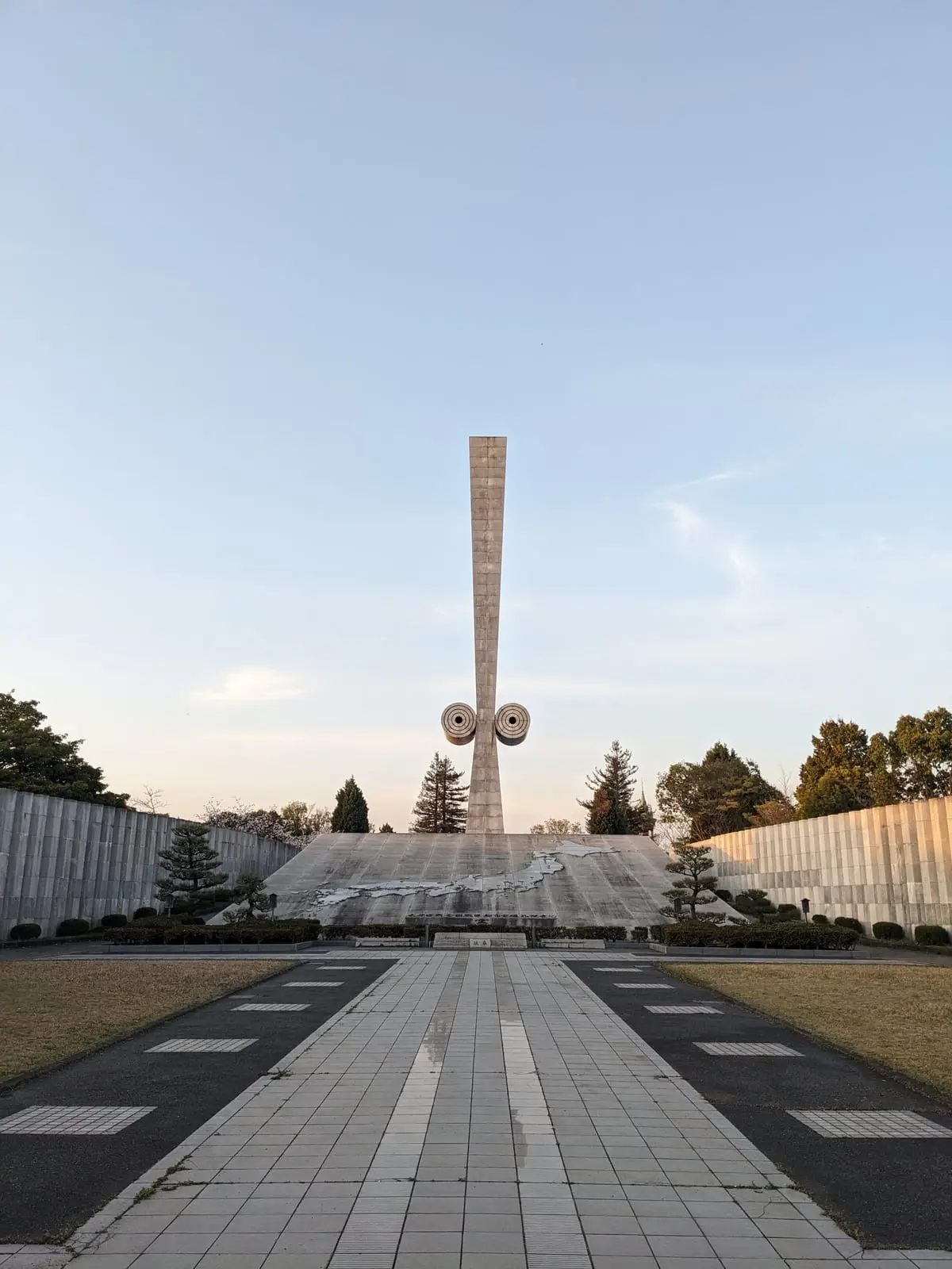 A tall stone monument with cherry blossoms in the foreground, under a clear blue sky