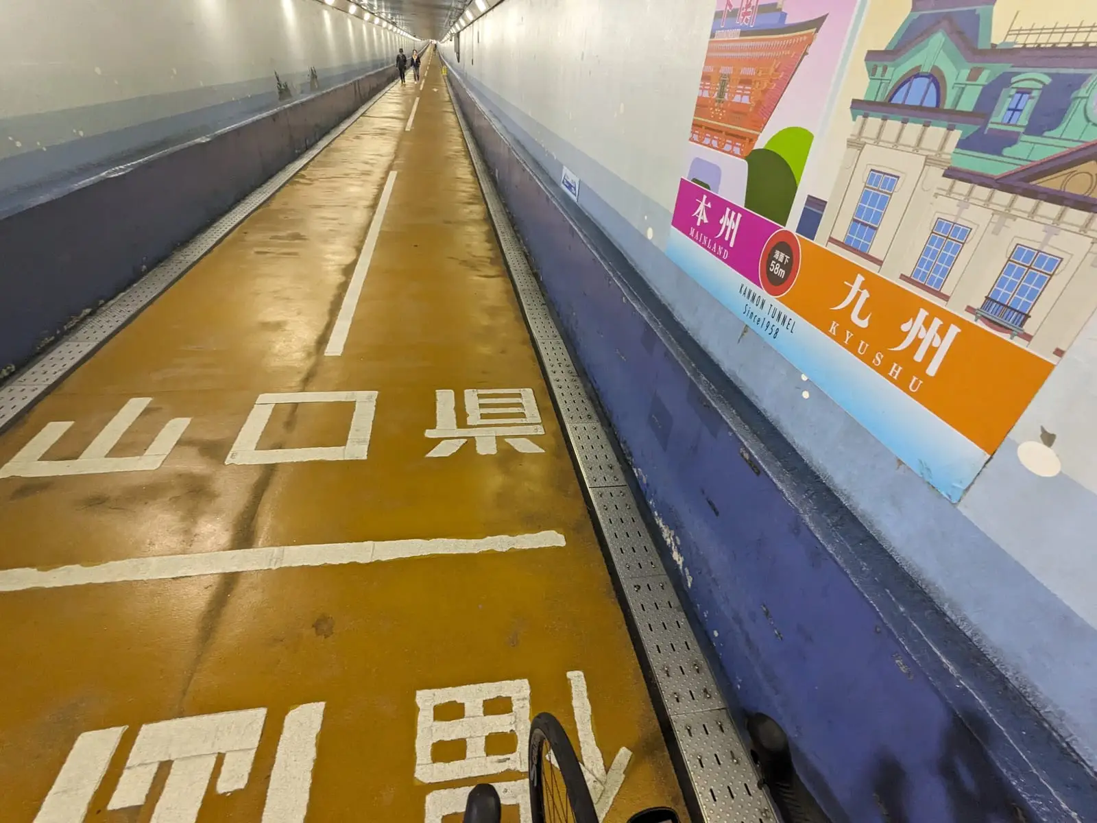 An orange-lit tunnel floor with a Japanese road sign reading Yamaguchi Prefecture on the wall